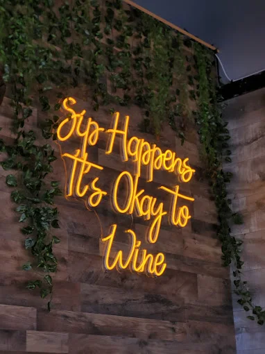 Neon sign in a cozy restaurant: Sip Happens, It's Okay to Wine