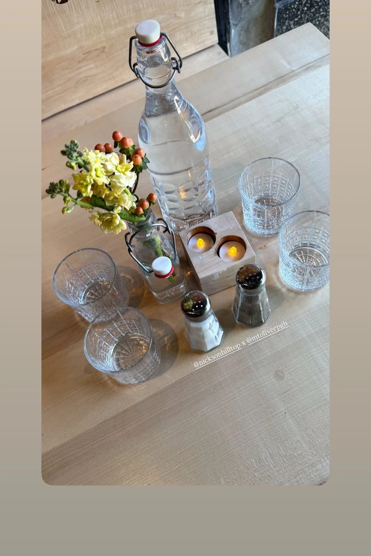 Table setting with water, glasses, and candles in a cozy restaurant