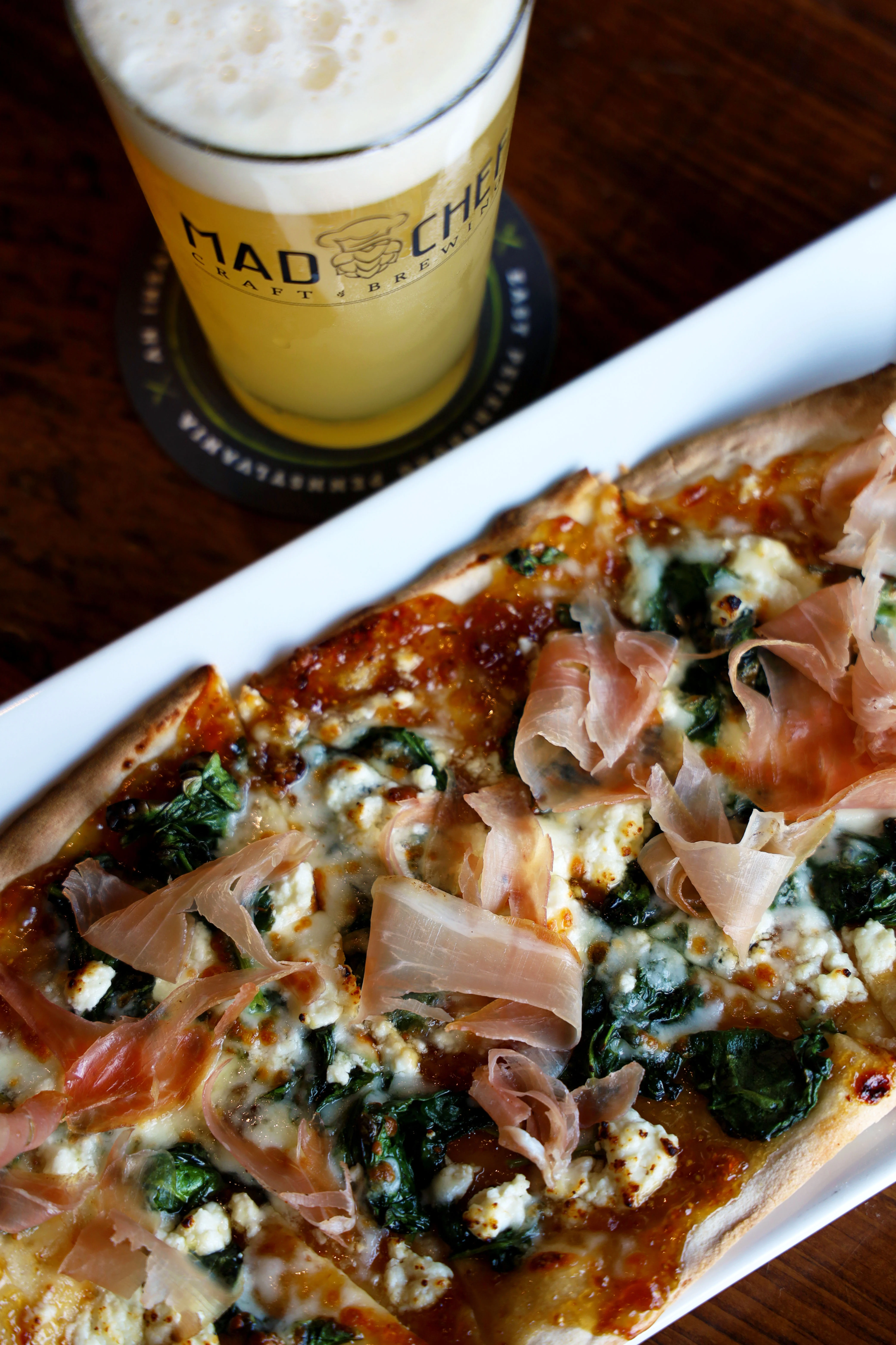 Flatbread pizza topped with spinach and prosciutto