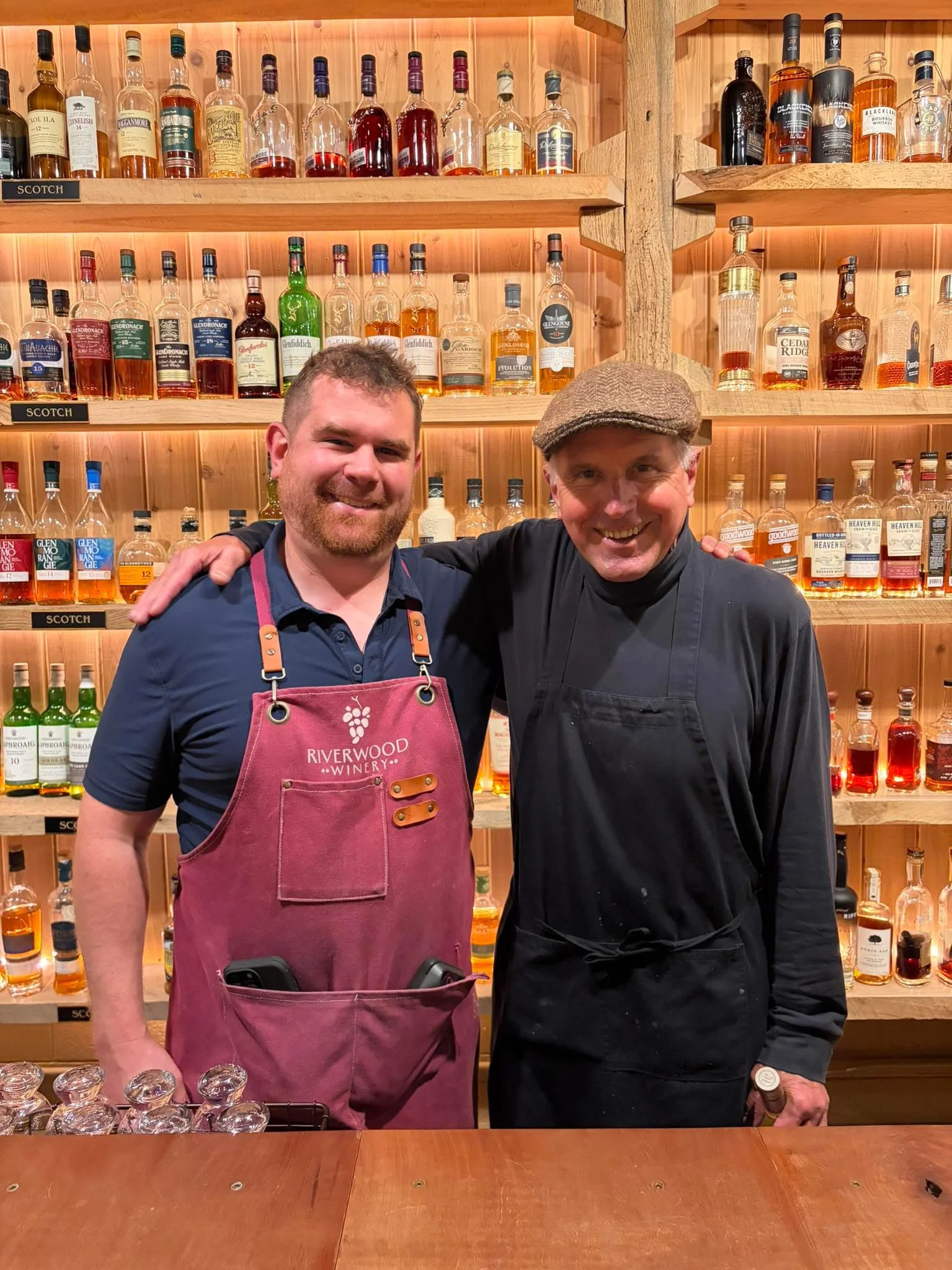 Bartenders posing in front of a whiskey shelf at a winery