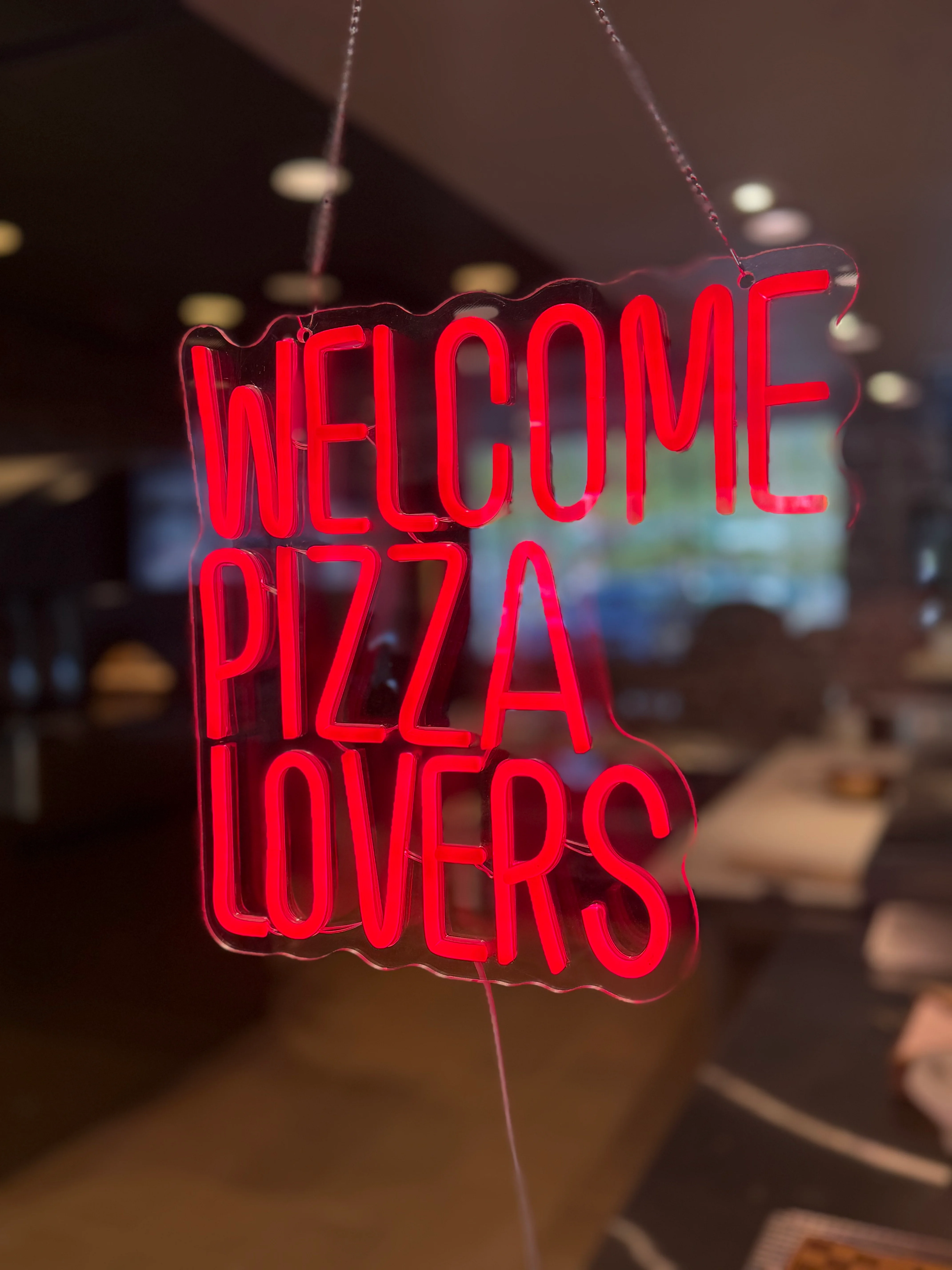 Neon sign welcoming pizza lovers to a cozy restaurant