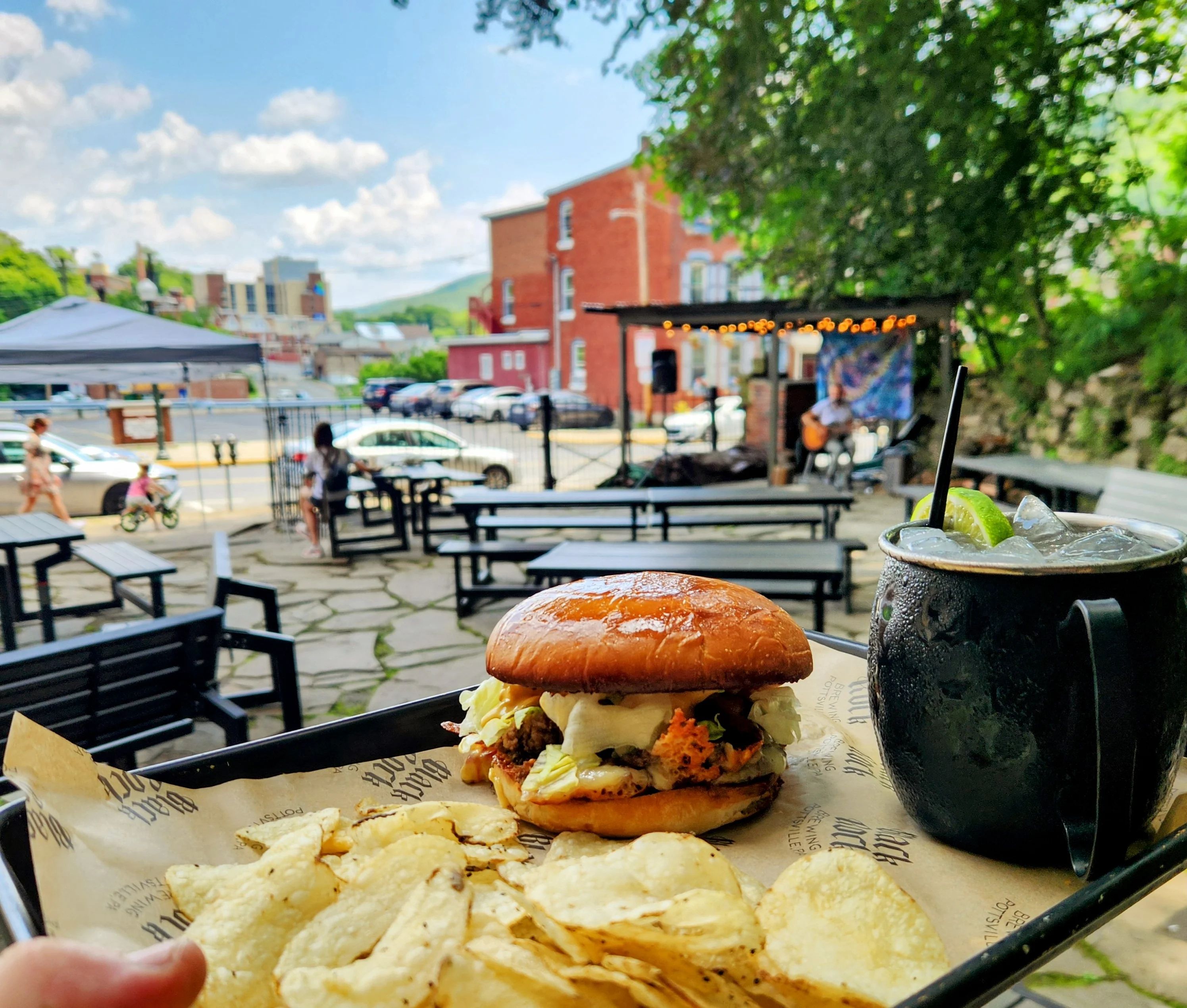 Crispy fried chicken sandwich with chips in a vibrant outdoor setting