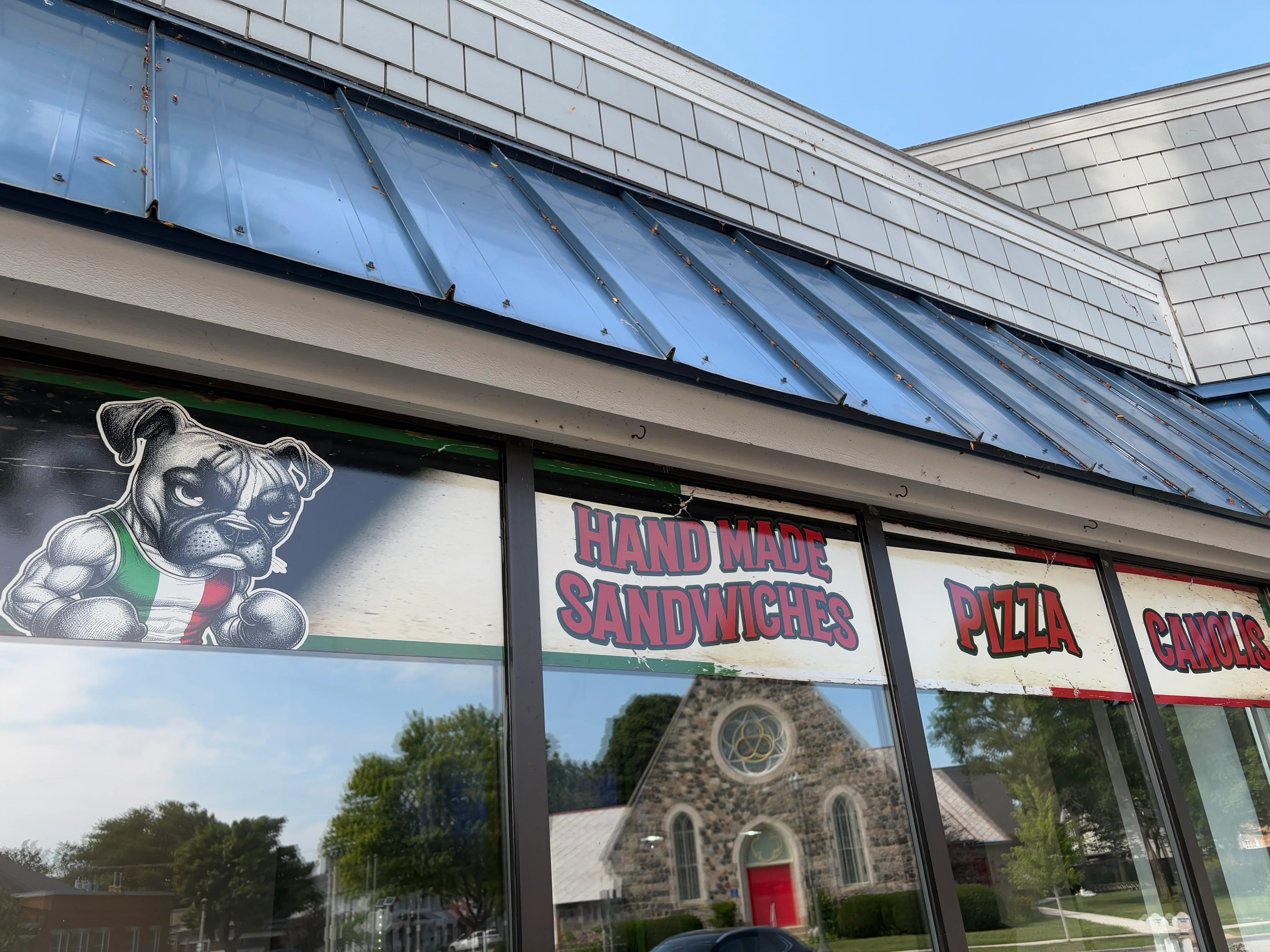 Restaurant window featuring handmade sandwiches and pizza