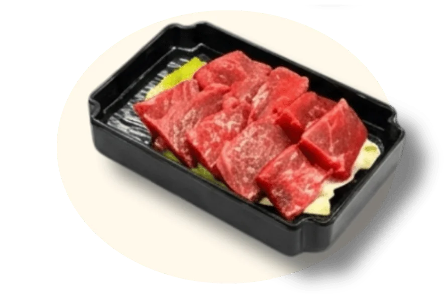 Sliced raw beef on a bed of vegetables in a black tray.