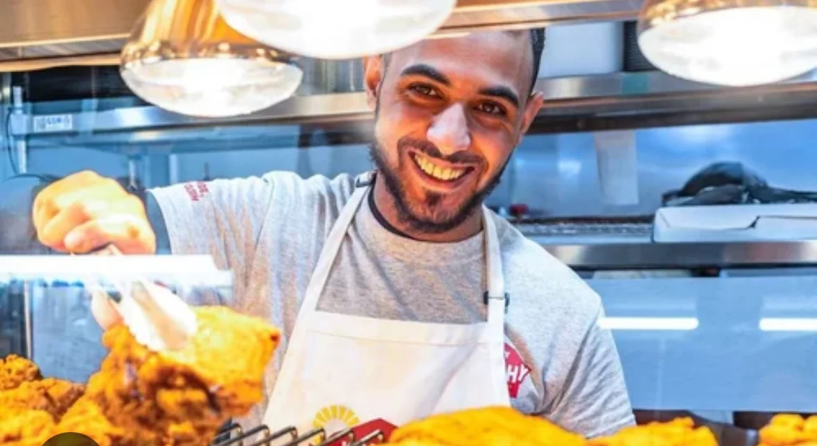 Smiling chef serving crispy fried chicken in a restaurant