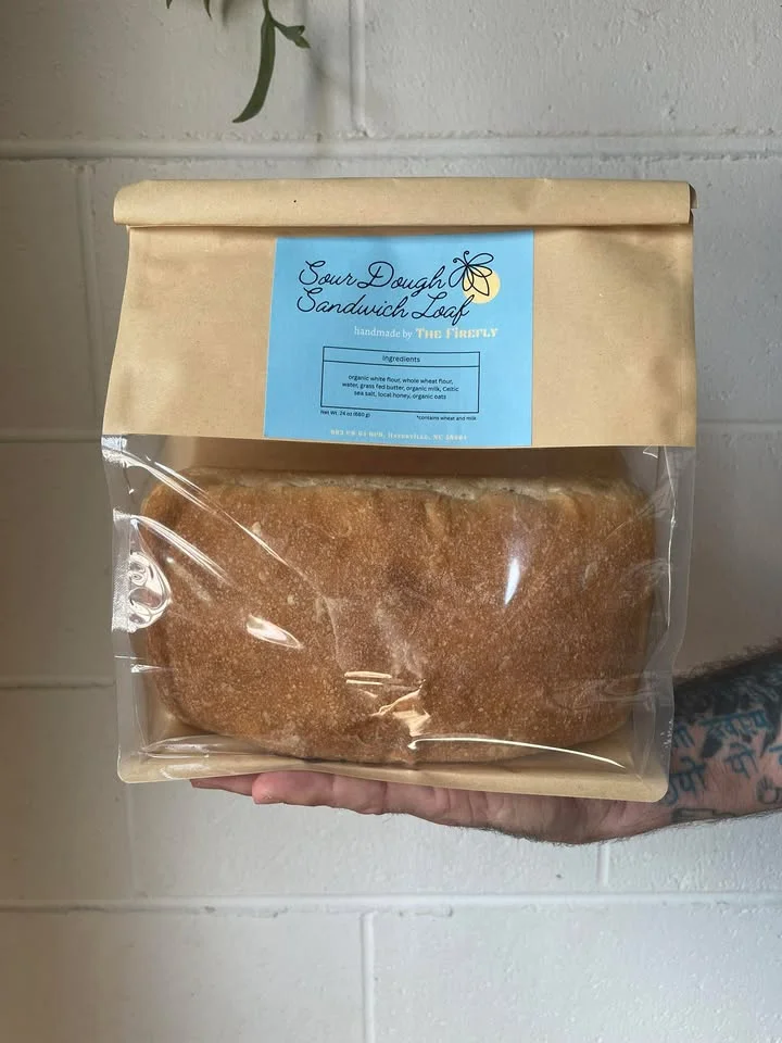 A packaged sourdough sandwich loaf labeled with ingredients and branding from an artisanal bakery.