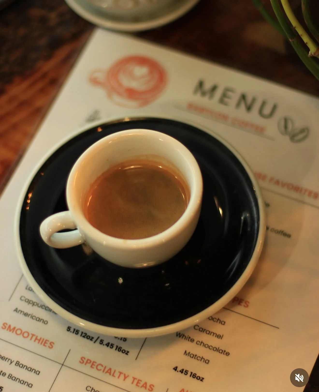 A small espresso cup on a black saucer, placed on a menu in a café.