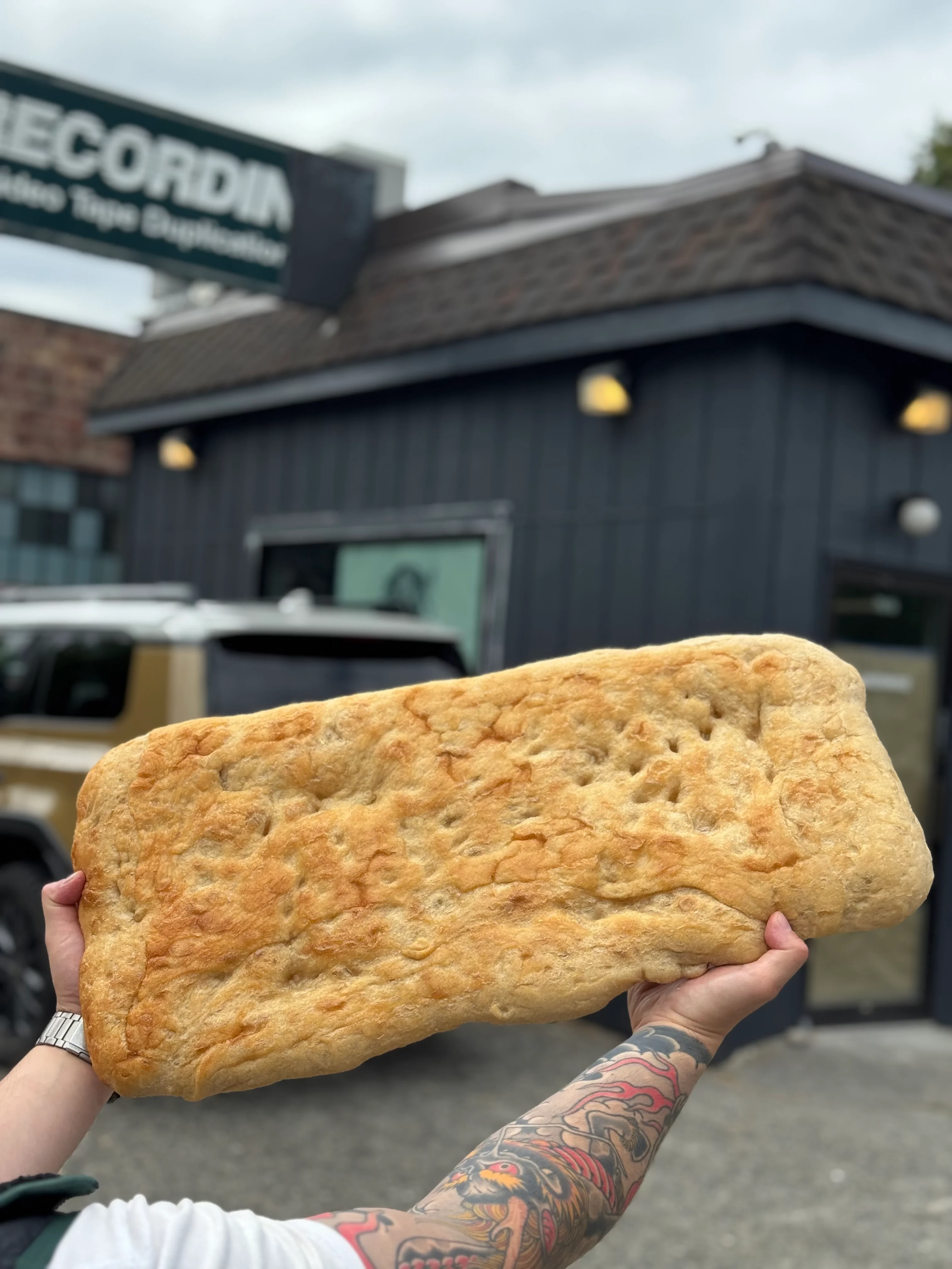 Large focaccia bread held outside a restaurant