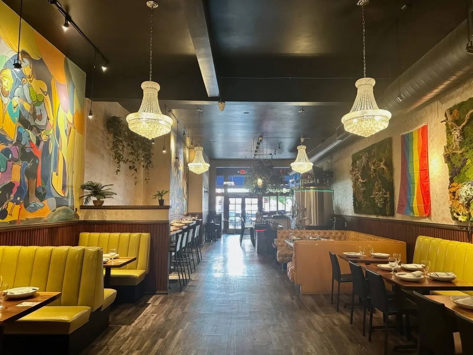 Castro Indian Restaurant dining room with chandeliers, yellow booths, colorful murals and lounge seating