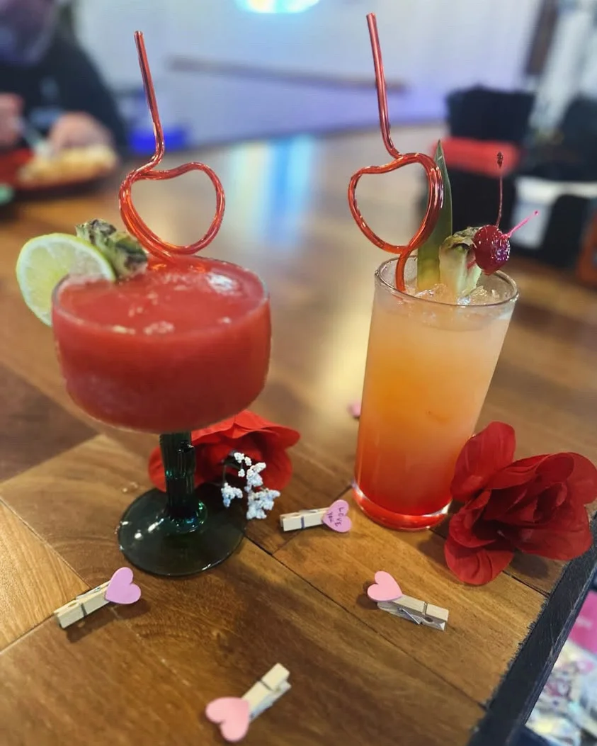 Colorful cocktails with heart-shaped straws on a wooden table