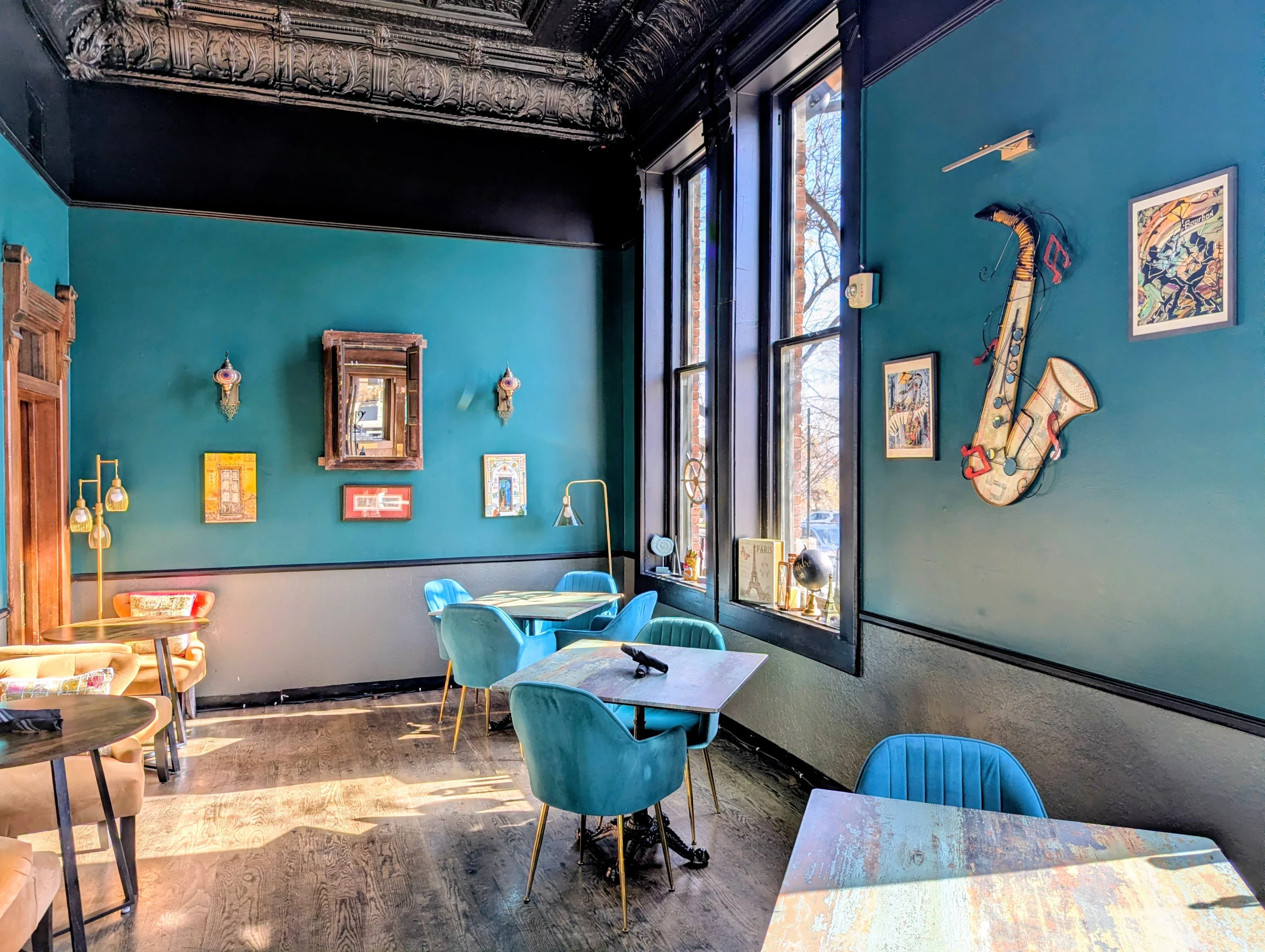 Elegant restaurant dining room with teal walls, ornate ceiling, and blue velvet chairs