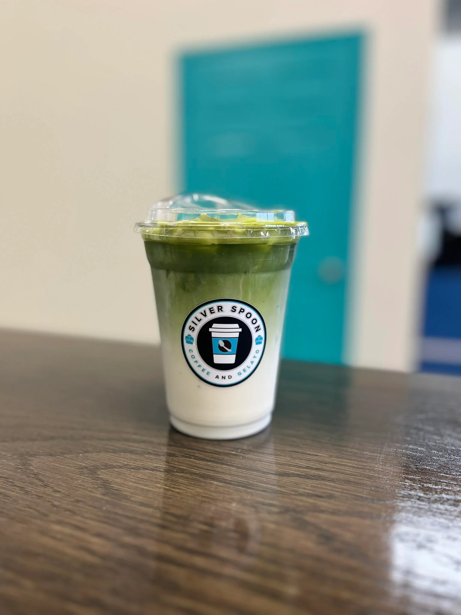 A vibrant matcha drink served in a clear glass with a frothy top.