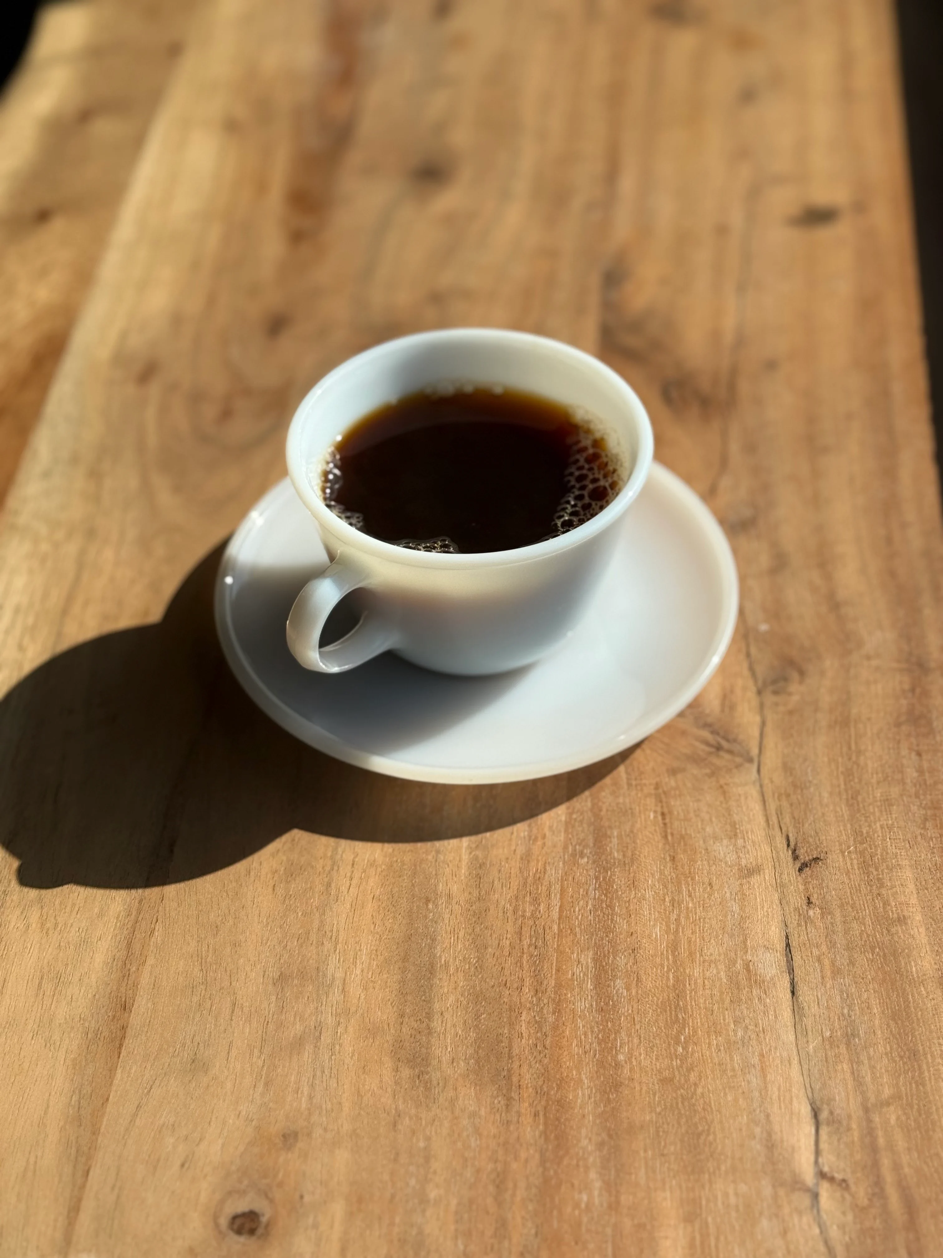 Freshly brewed coffee in a white cup on a wooden table