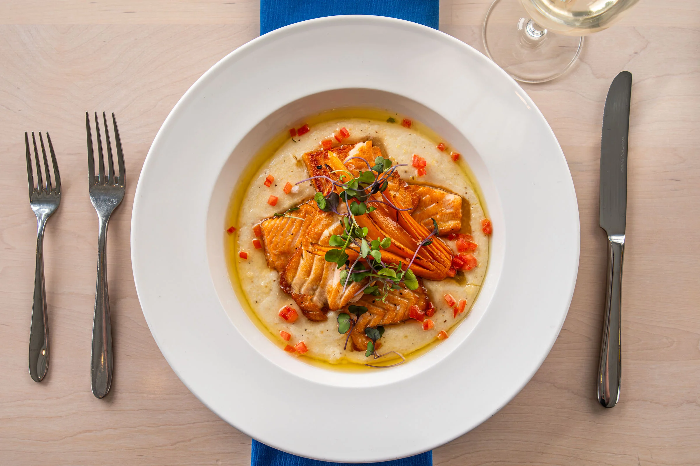 Grilled salmon served with roasted vegetables and baby potatoes on a rectangular plate.