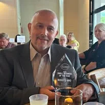 Award-winning restaurateur holding a trophy in a dining setting
