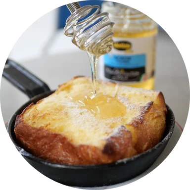 French toast drizzled with honey in a cast iron skillet