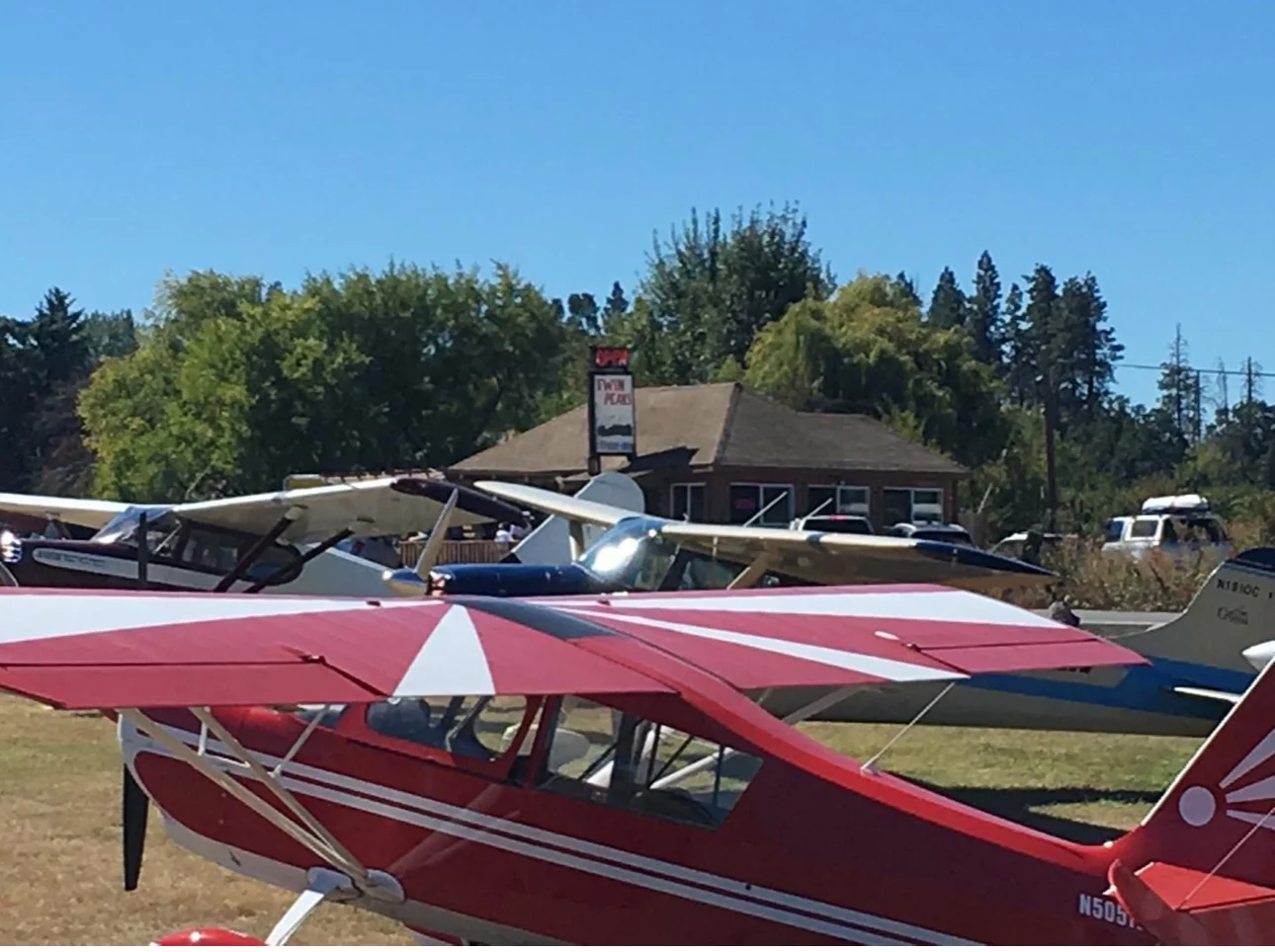 Vintage aircraft parked near a restaurant with a sign