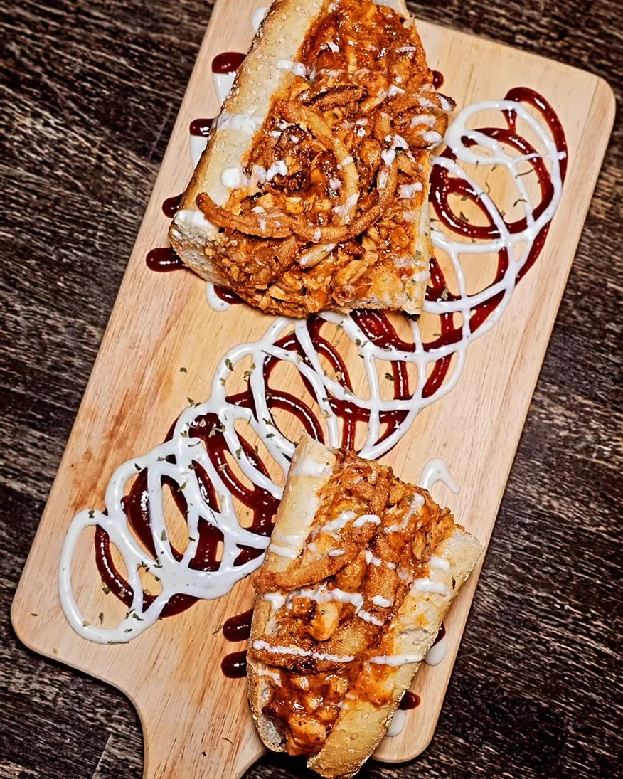 Half hot dog topped with condiments on a plate.