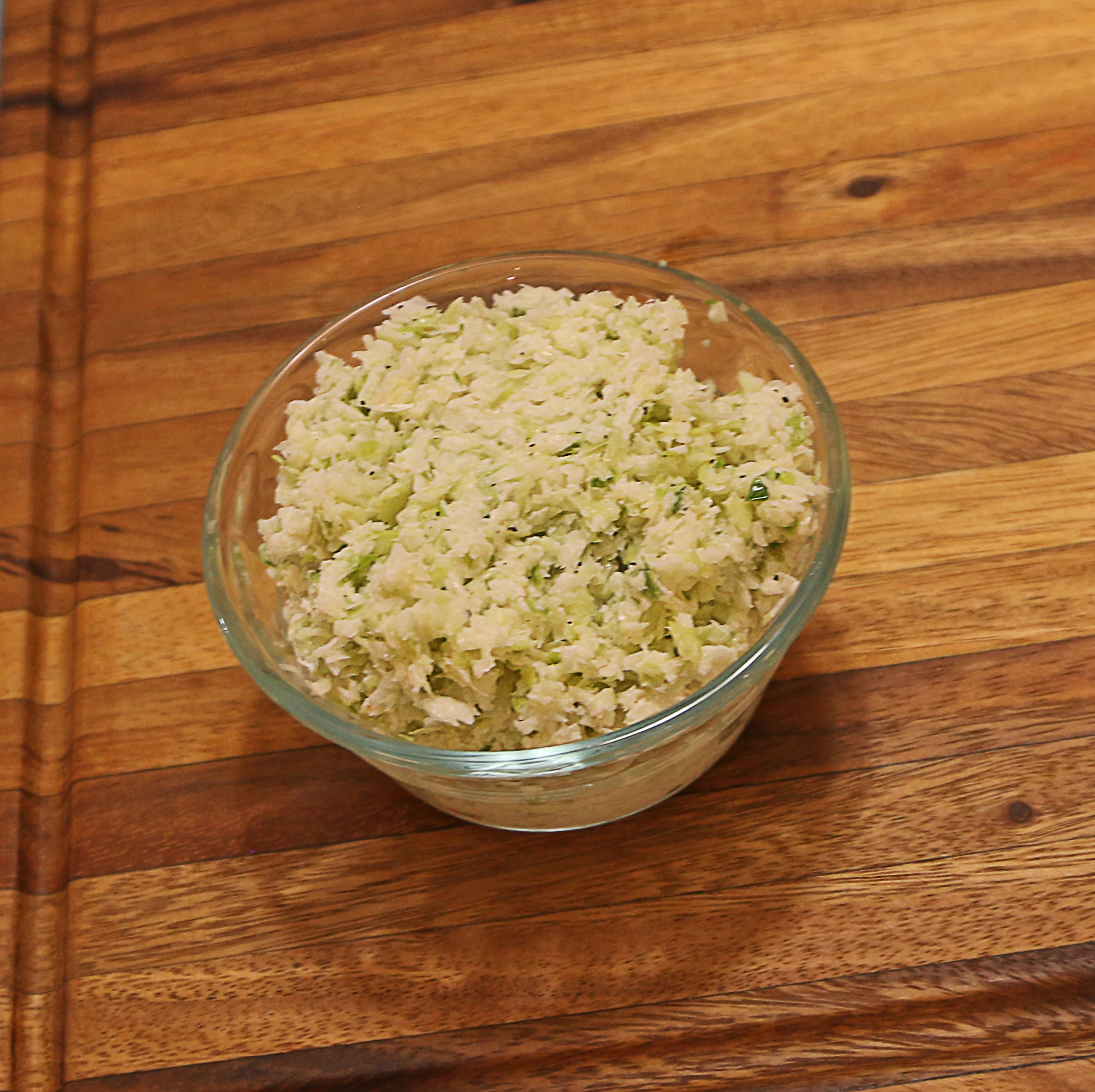 A bowl of finely shredded coleslaw made from cabbage and other ingredients, presented in a glass bowl.