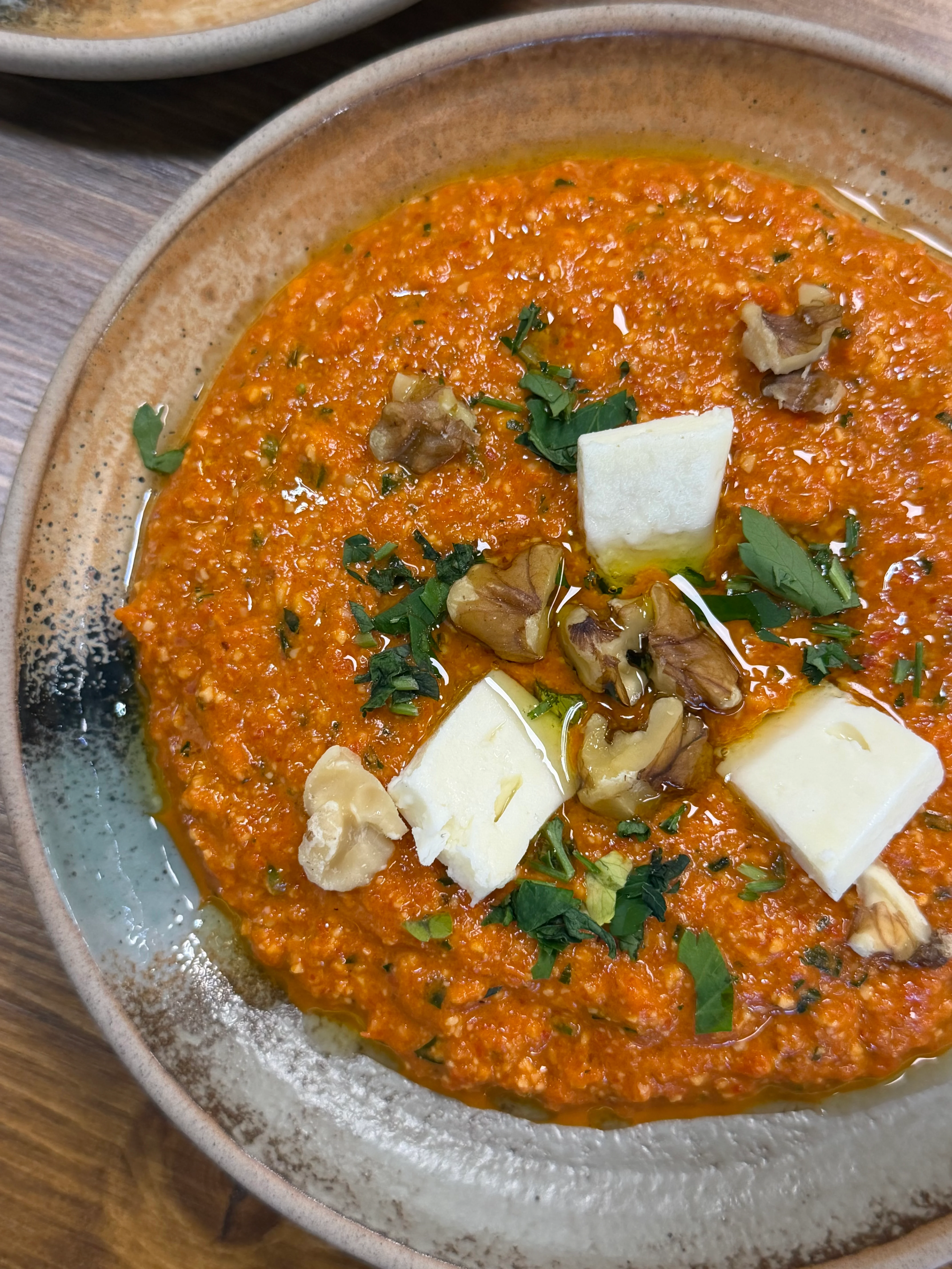 Turkish muhammara dip garnished with walnuts and herbs