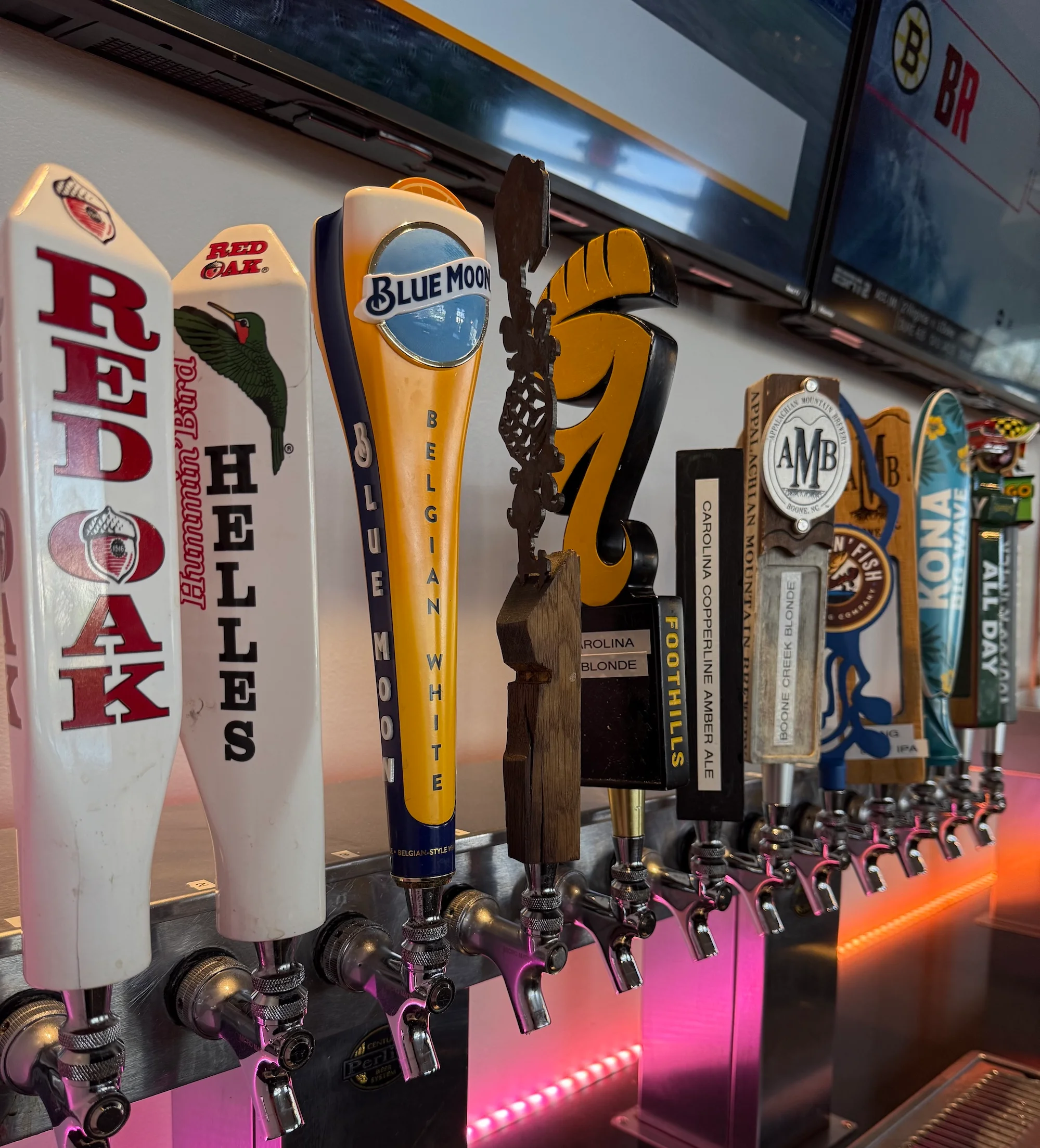 Variety of beer taps with colorful handles at a bar.