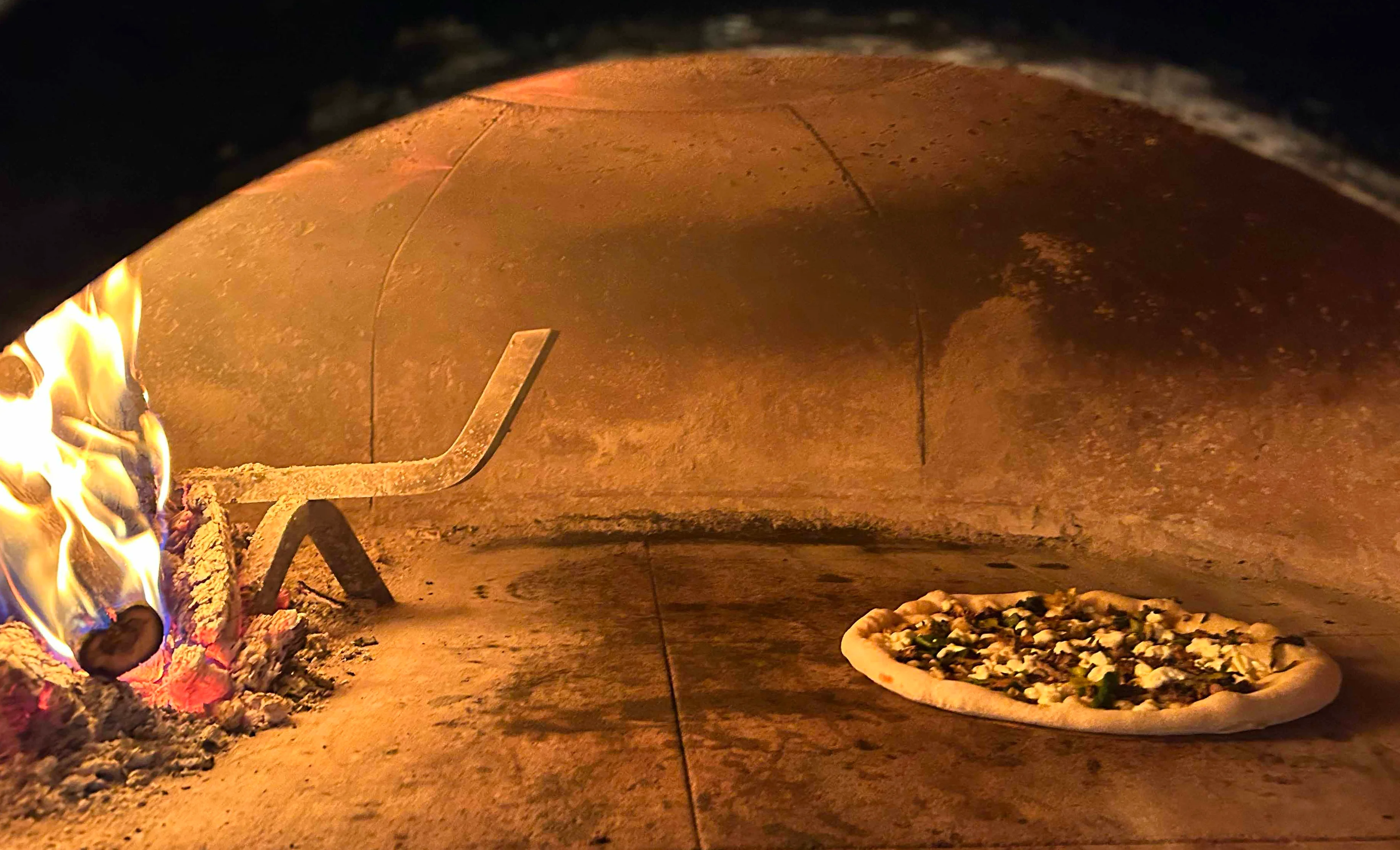 Wood-fired pizza baking in a traditional oven