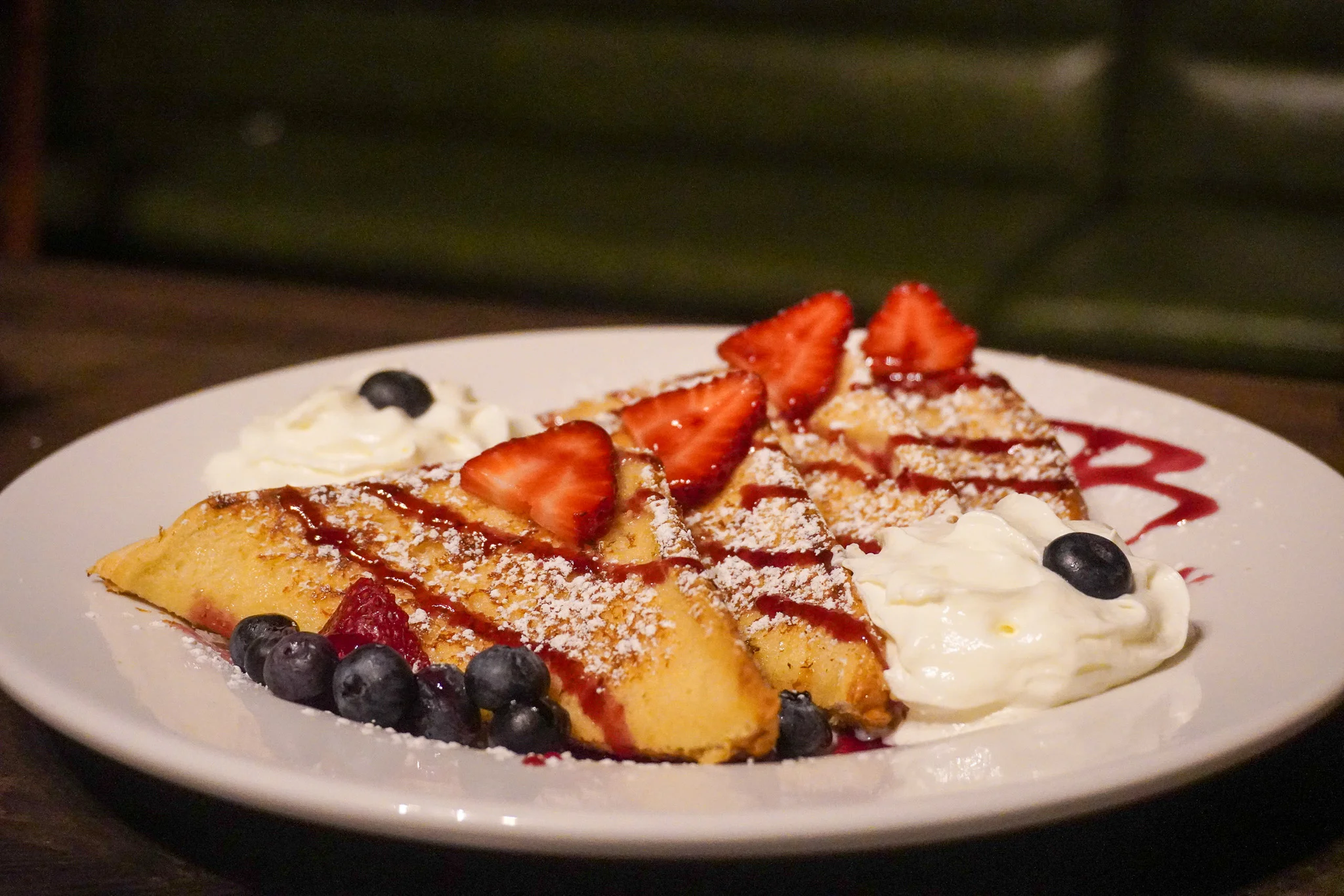 Delicious French crepes topped with strawberries and blueberries, served with whipped cream