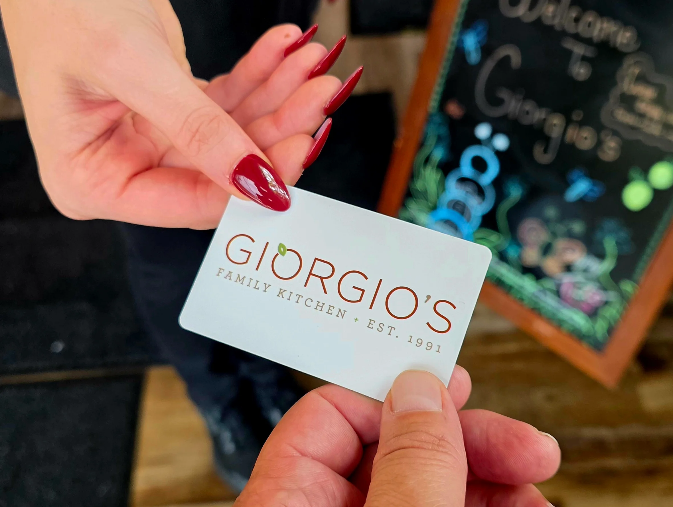 A hand holding a Giorgio's Family Kitchen loyalty card.