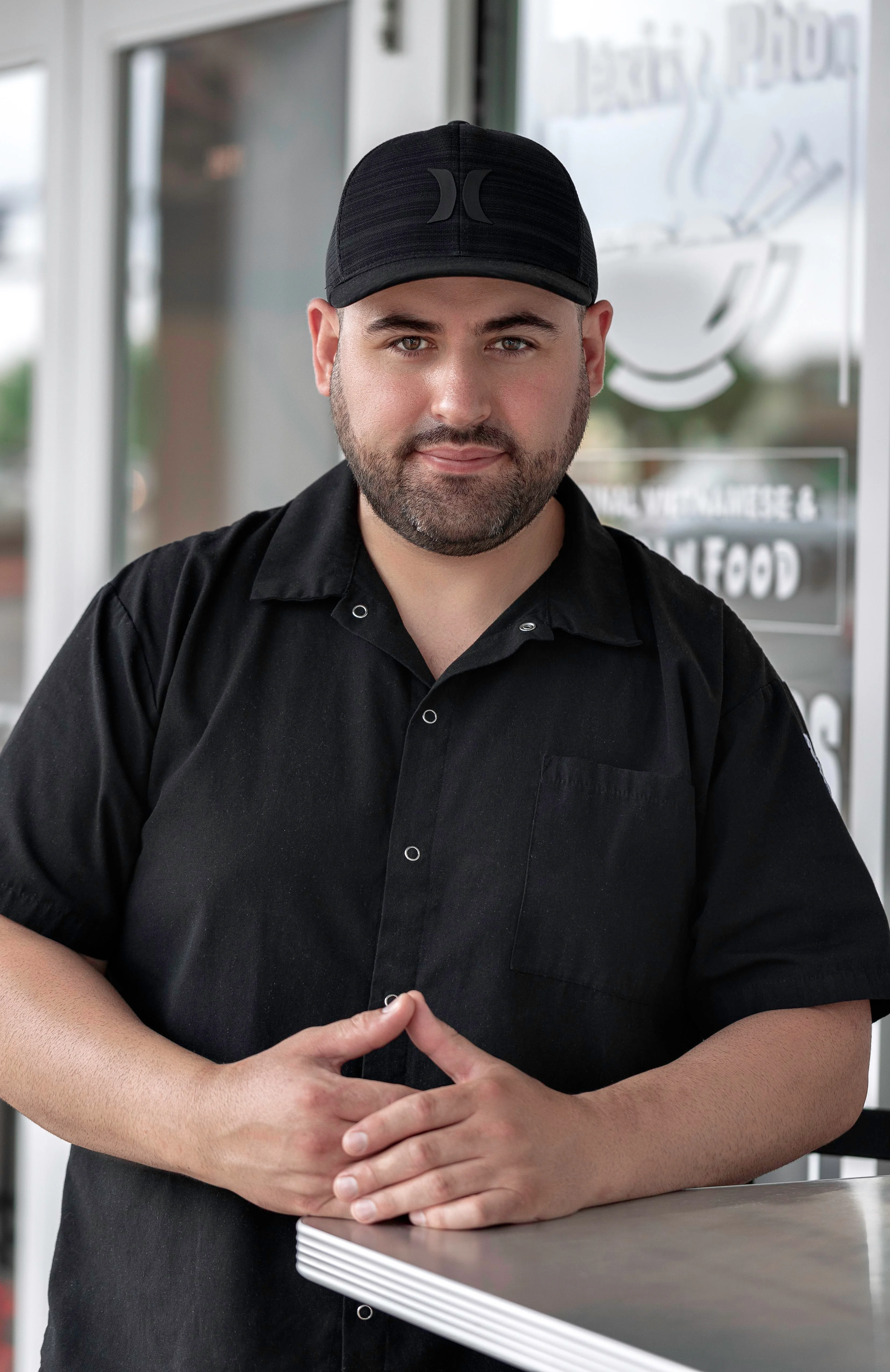 Restaurant owner posing in front of a Vietnamese pho shop