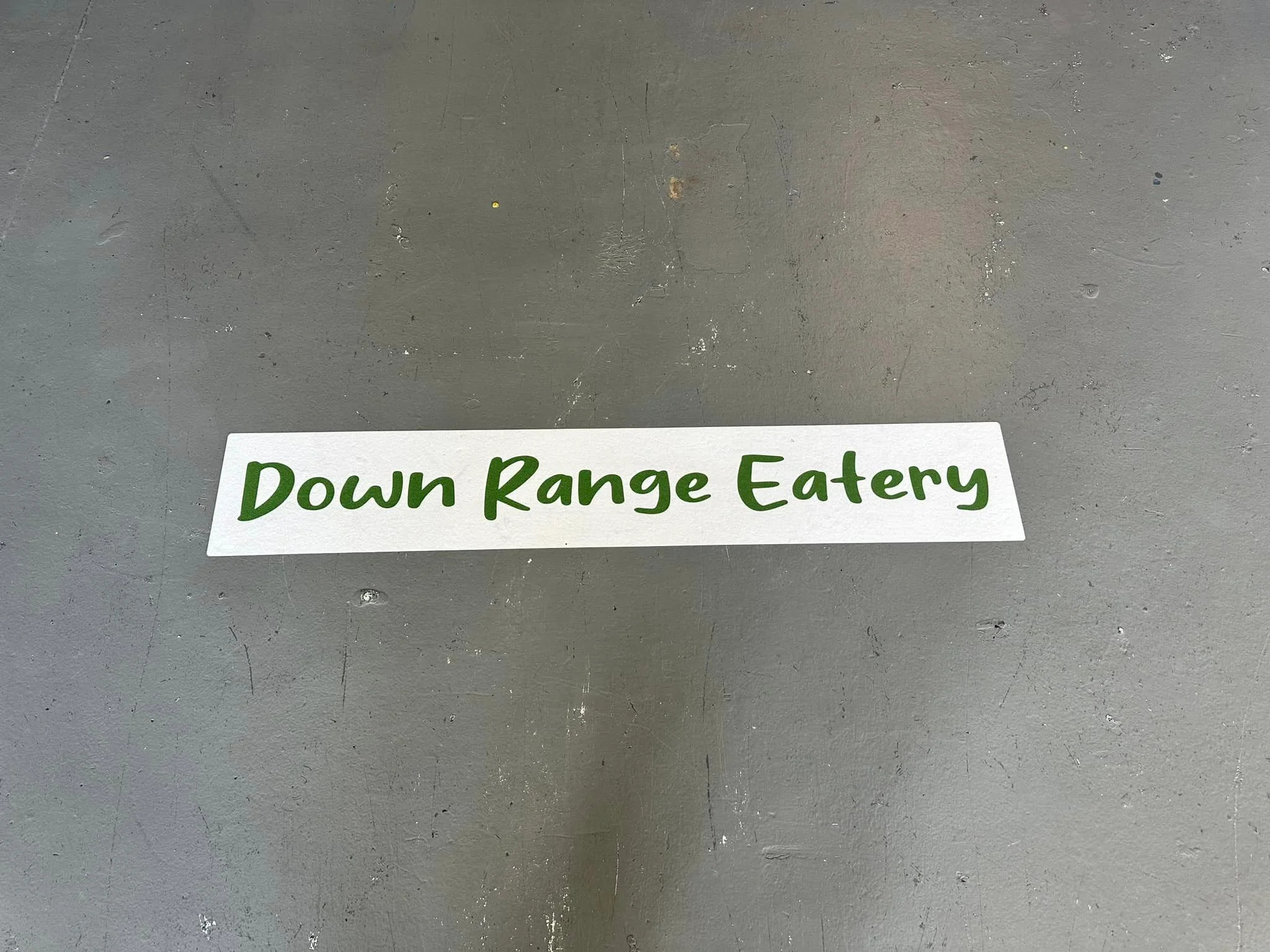 Signage for Down Range Eatery on a rustic surface