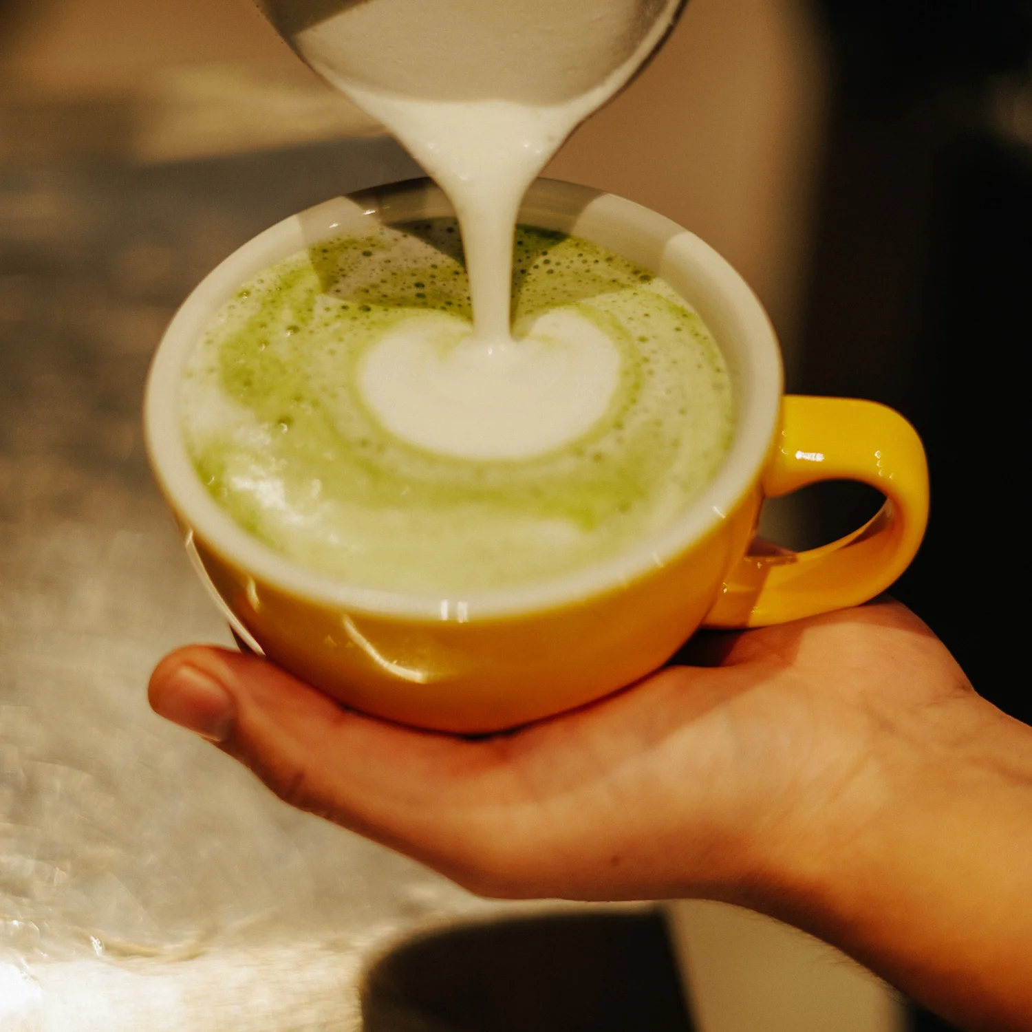 Matcha latte art in a vibrant yellow cup