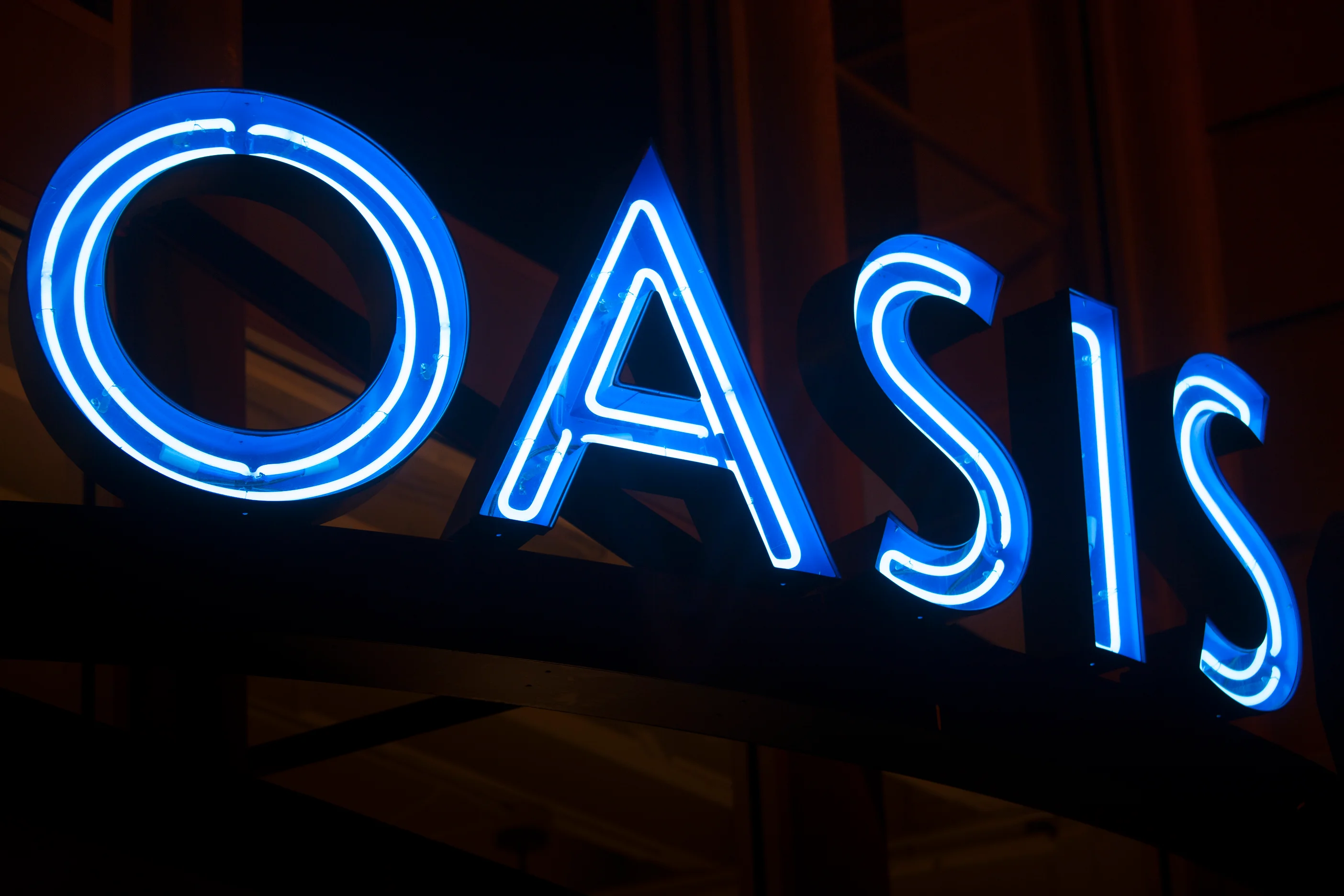 Neon sign of 'Oasis' restaurant glowing at night