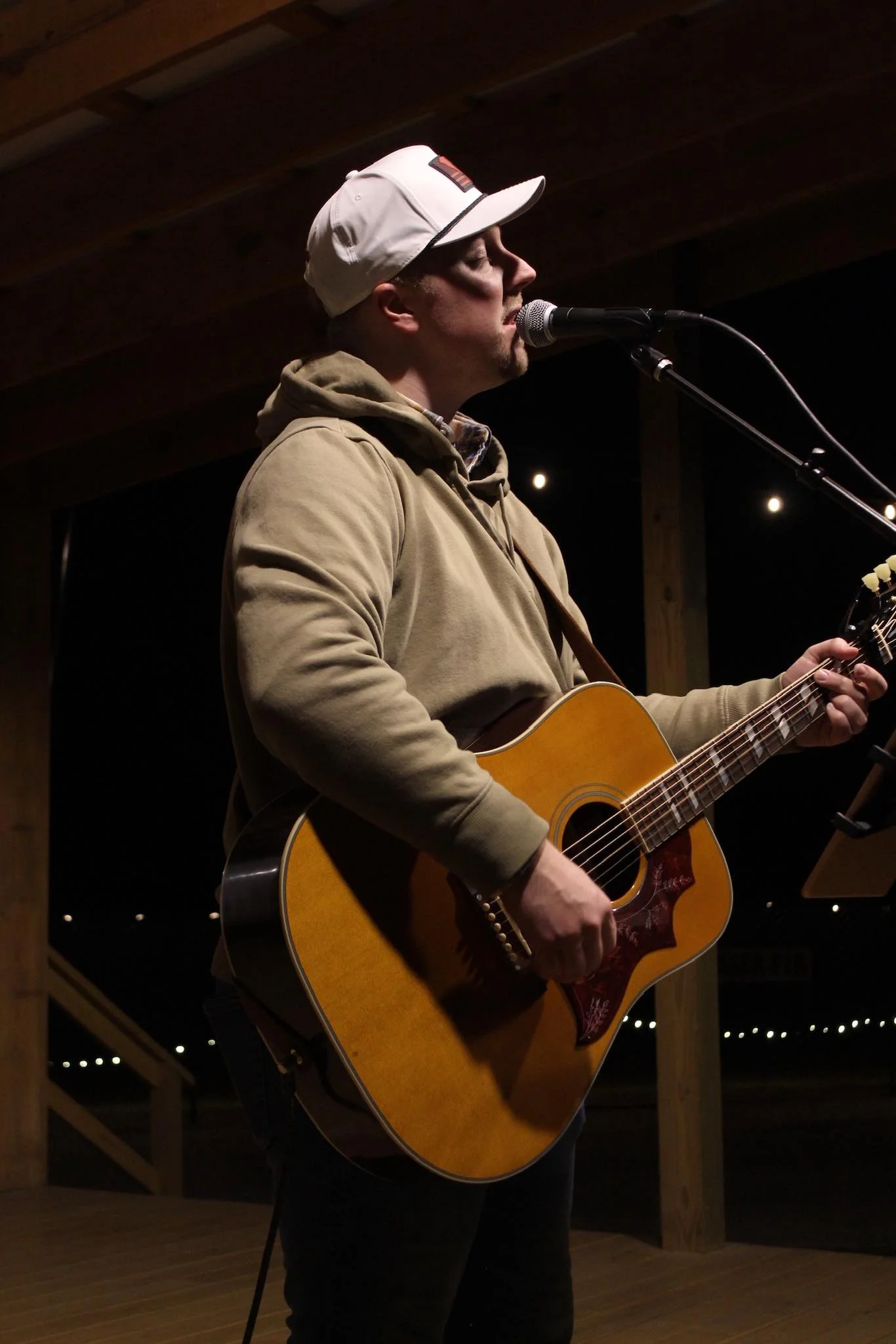 Musician performing live with acoustic guitar on stage