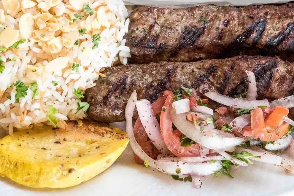 Grilled kebabs served with rice and fresh salad, a Middle Eastern delight