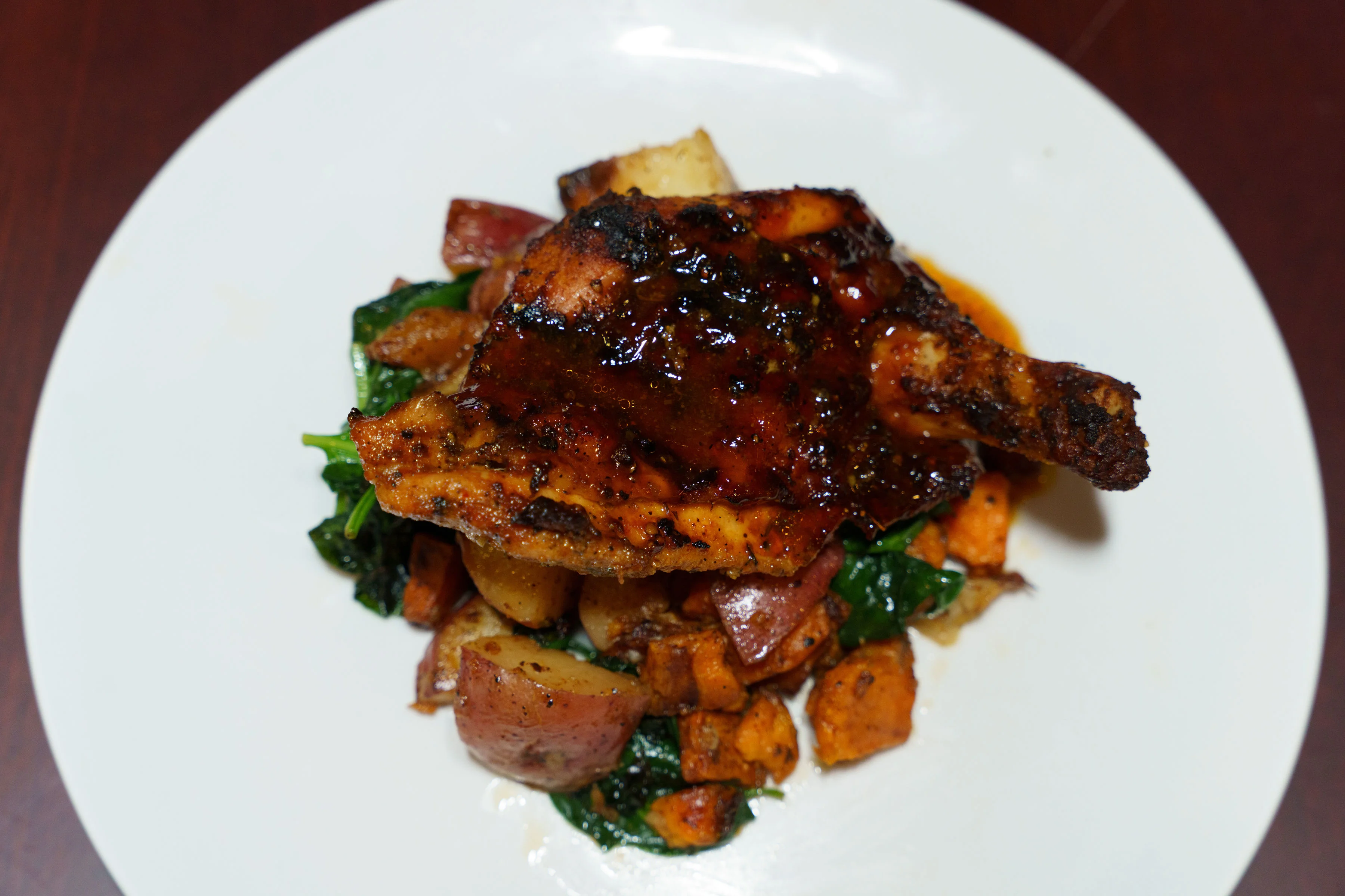 Grilled jerk chicken served with sweet potatoes and greens