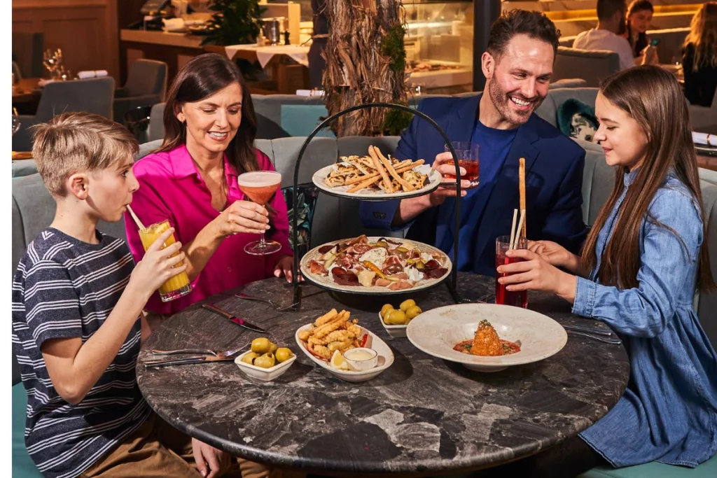 Family enjoying a meal at a restaurant with drinks and appetizers.