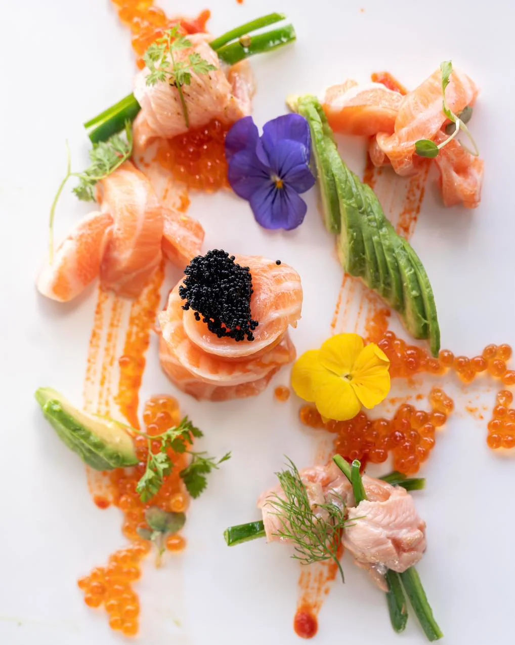 Artistic salmon sashimi platter with caviar and edible flowers