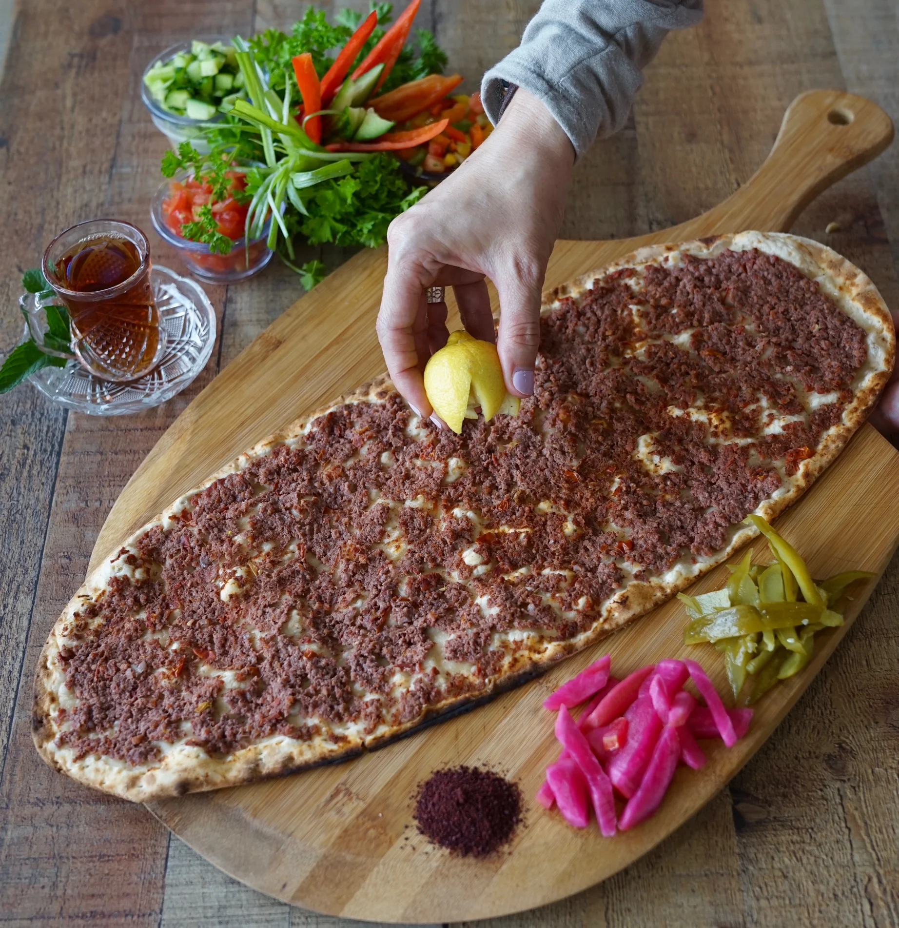 Turkish lahmacun topped with lemon and fresh herbs