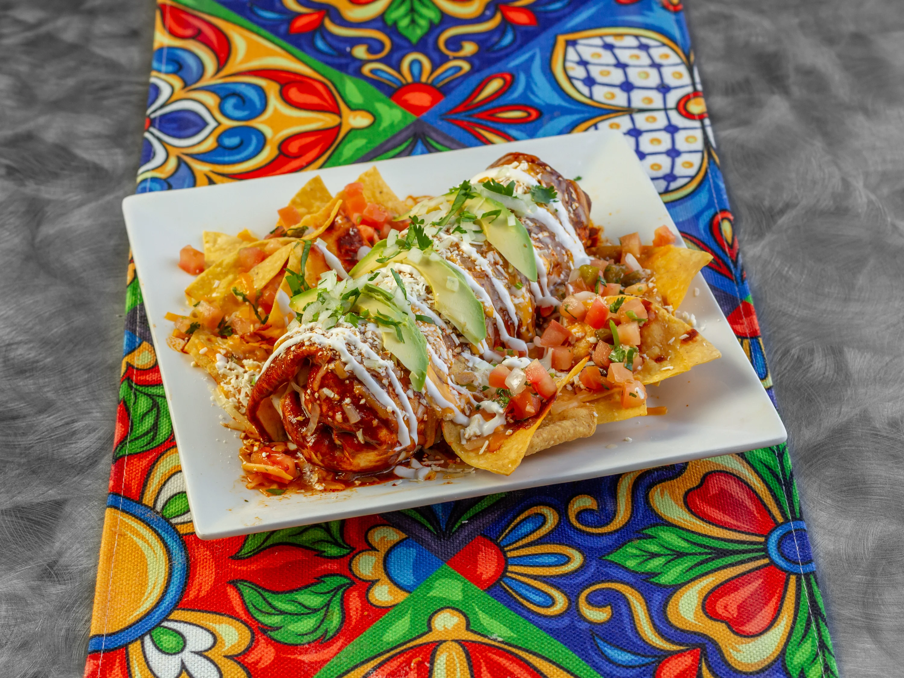 Plate of enchiladas topped with fresh salsa and crema