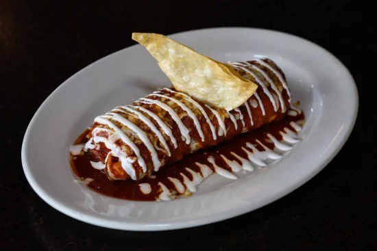 Delicious enchilada topped with sauce and crema