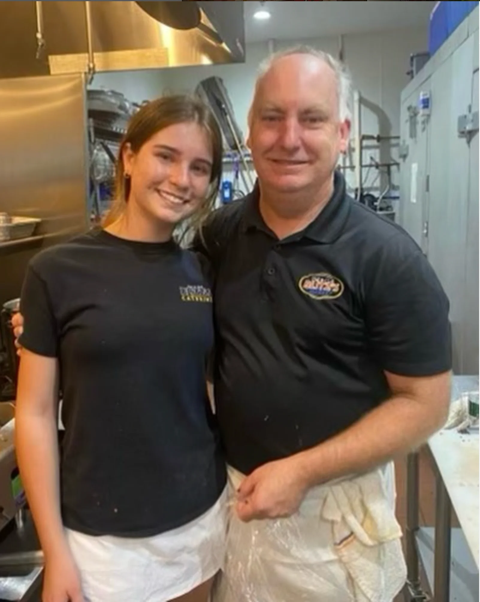 Chefs smiling together in a busy restaurant kitchen