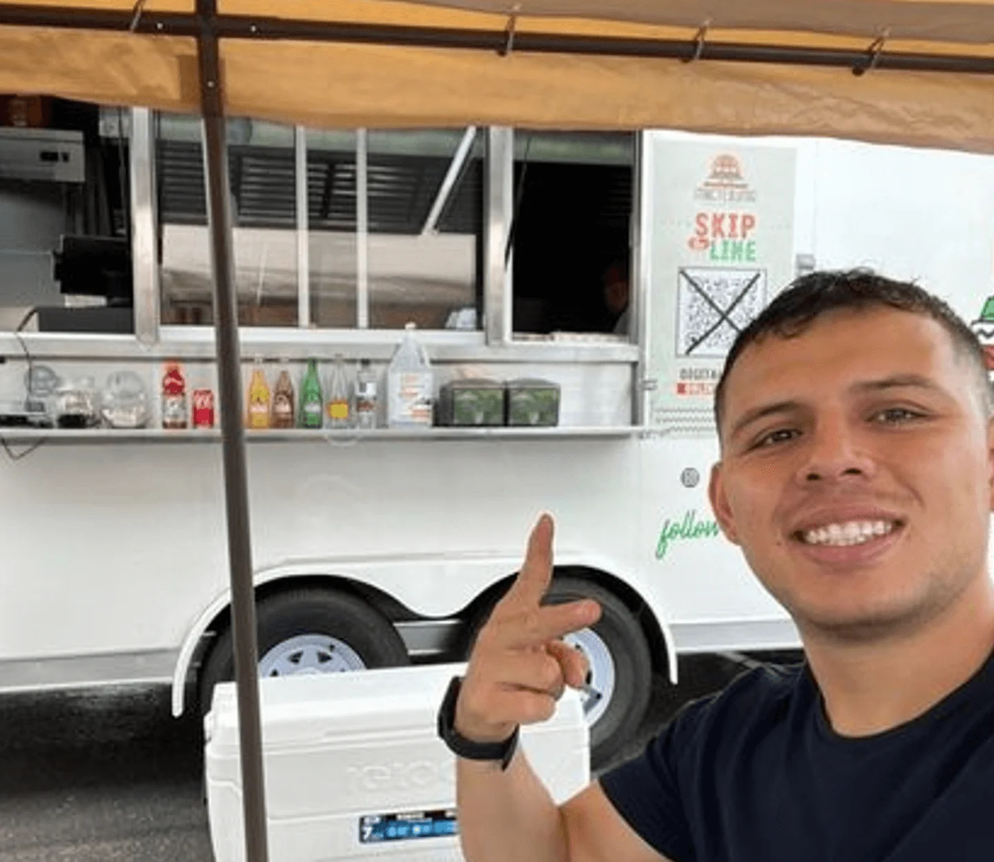 Food truck vendor smiling in front of a mobile kitchen