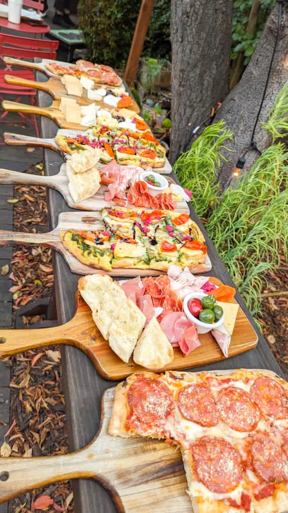 Assorted gourmet pizzas and antipasto platters on wooden boards