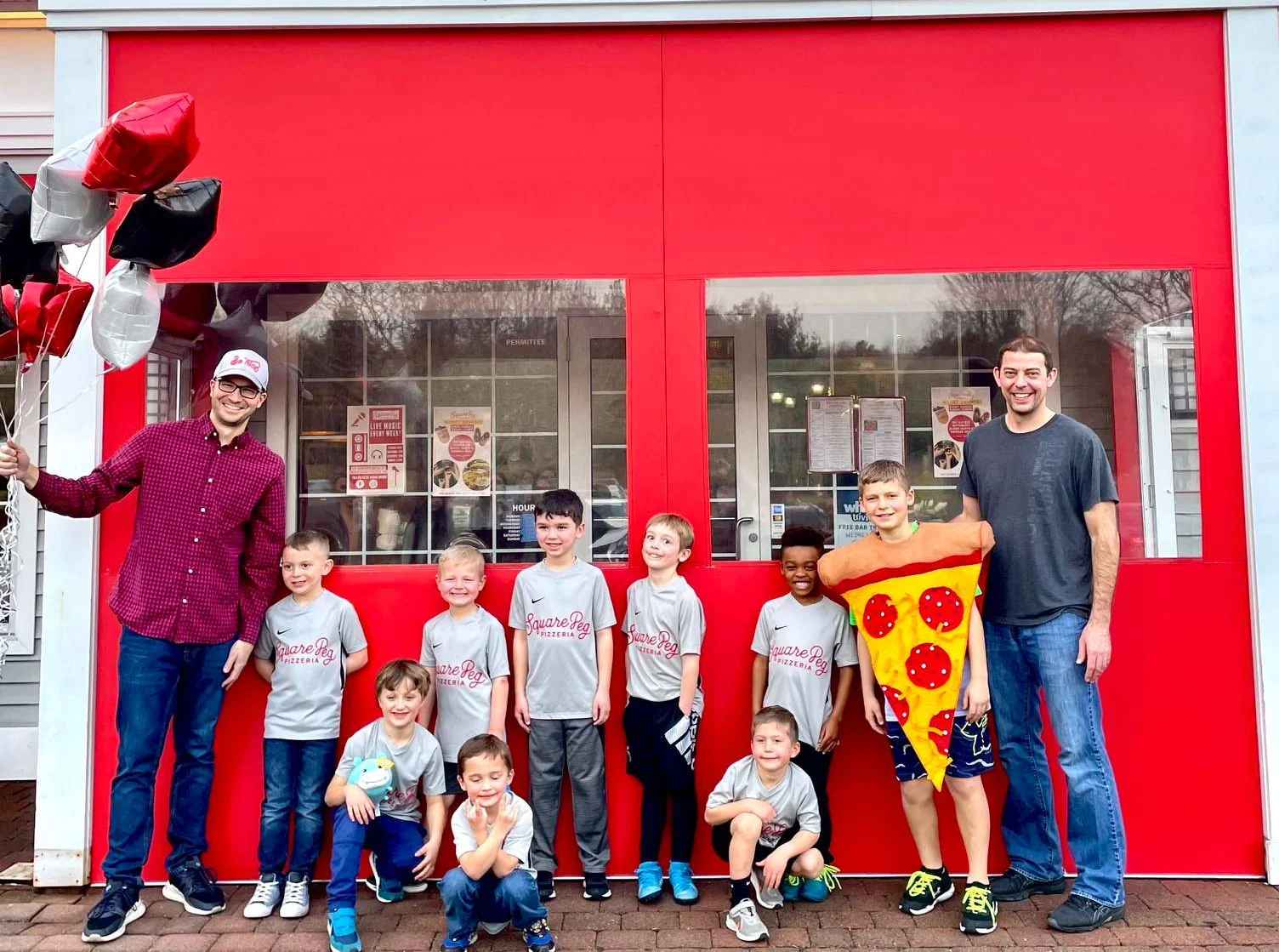 Children celebrating at Square Peg restaurant with balloons and pizza costume