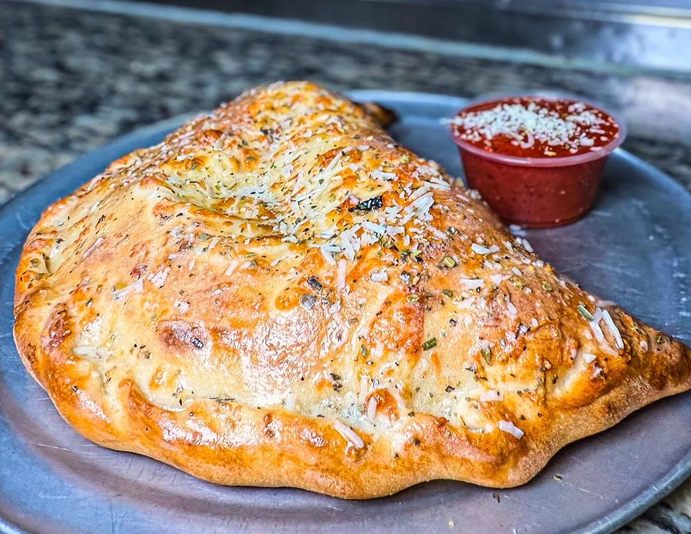 Cheese-loaded calzone baked golden brown, dusted with herbs and served with marinara for dipping