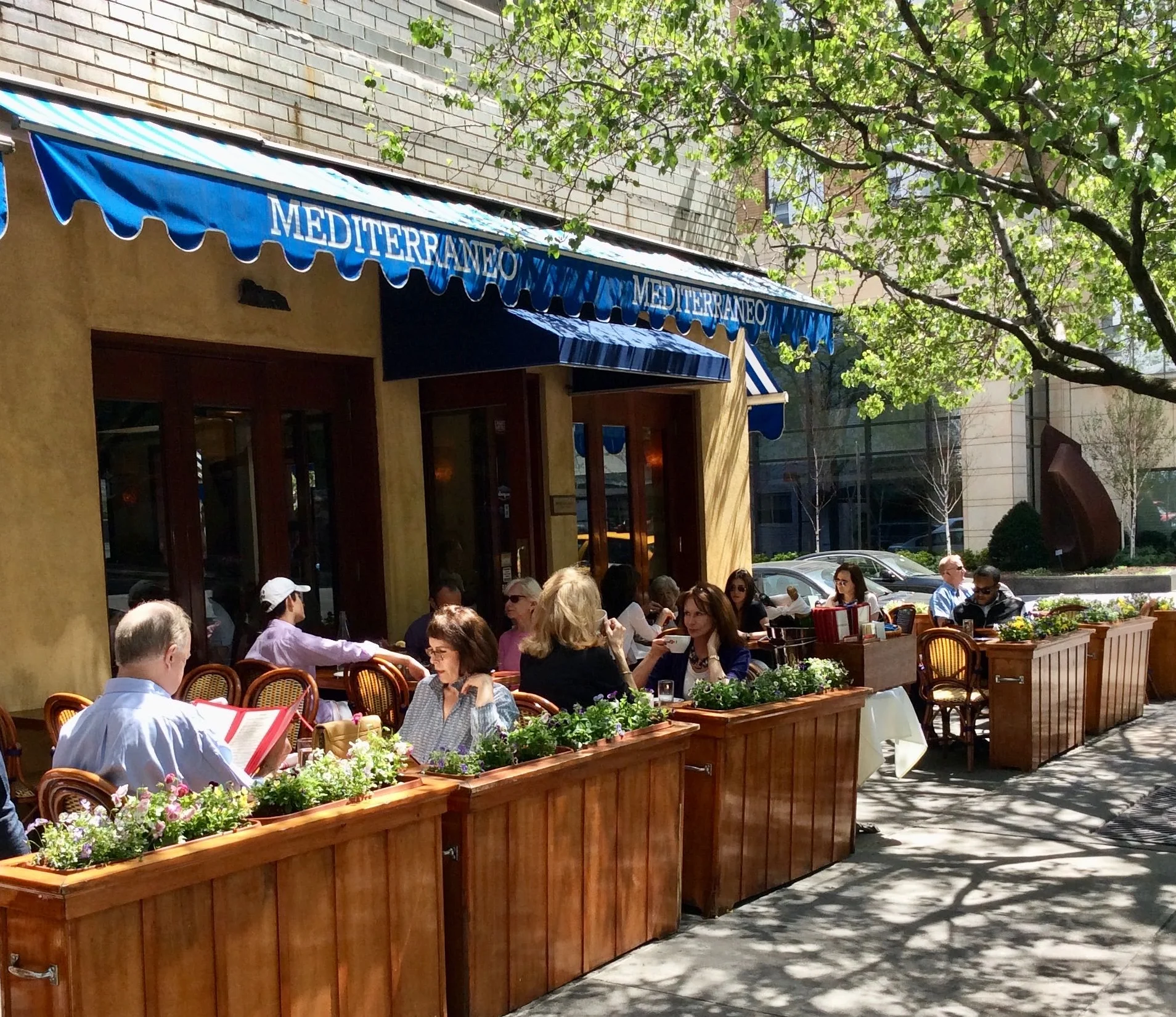 Outdoor dining area of a Mediterranean restaurant with patrons enjoying meals