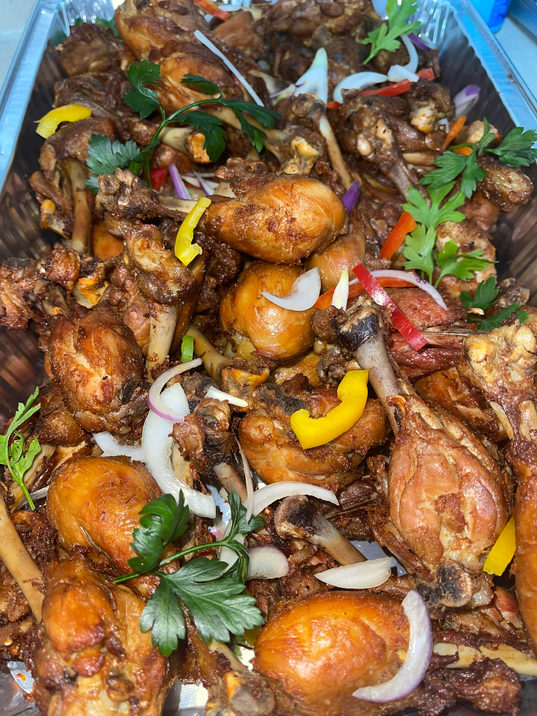 Crispy fried chicken drumsticks with colorful peppers and herbs