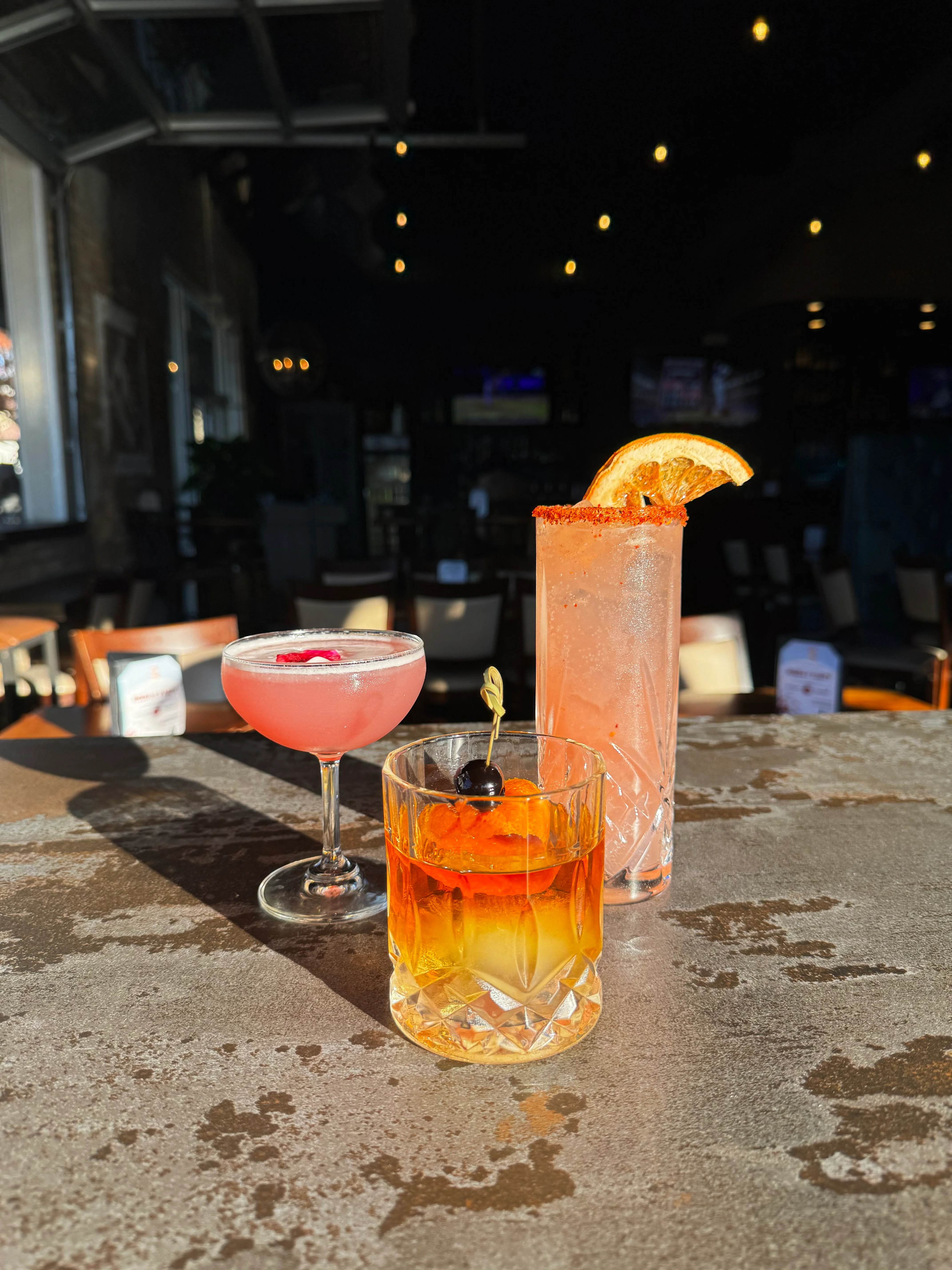 Colorful cocktails on a bar counter in a lively restaurant setting