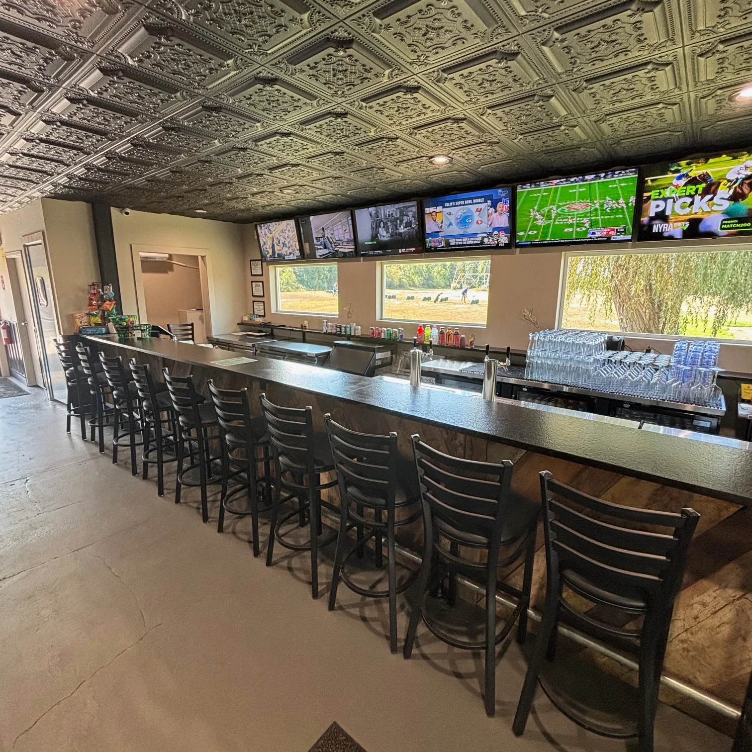 Modern bar interior with black stools and multiple TVs