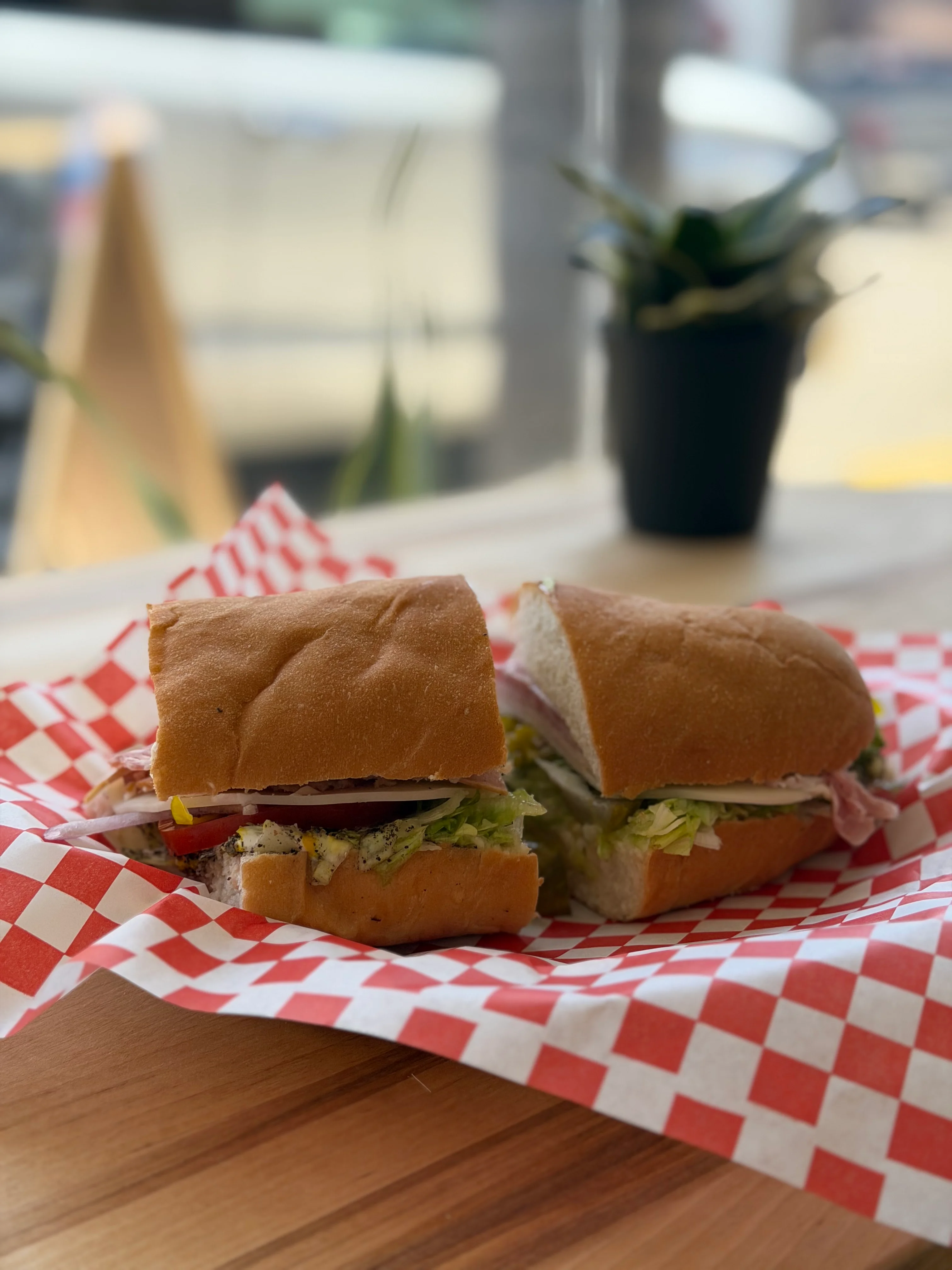 Classic deli sandwich on a wooden table with checkered paper